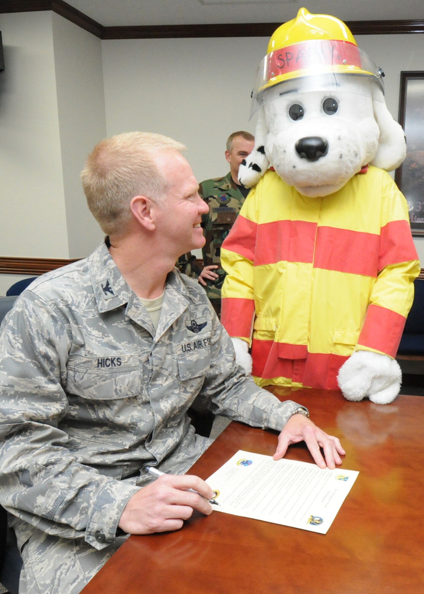 YOKOTA AIR BASE, Japan -- Col. J. Marcus Hicks, 374th Airlift Wing commander, signs a proclamation letter declaring Oct. 13-17 as fire prevention week here as Sparky the Fire Dog looks on. During fire prevention week the Yokota Fire Department will sponsor activities for children across the base to educate children and their parents on fire prevention and detection. (U.S. Air Force photo/Staff Sgt. Veronica Pierce)
