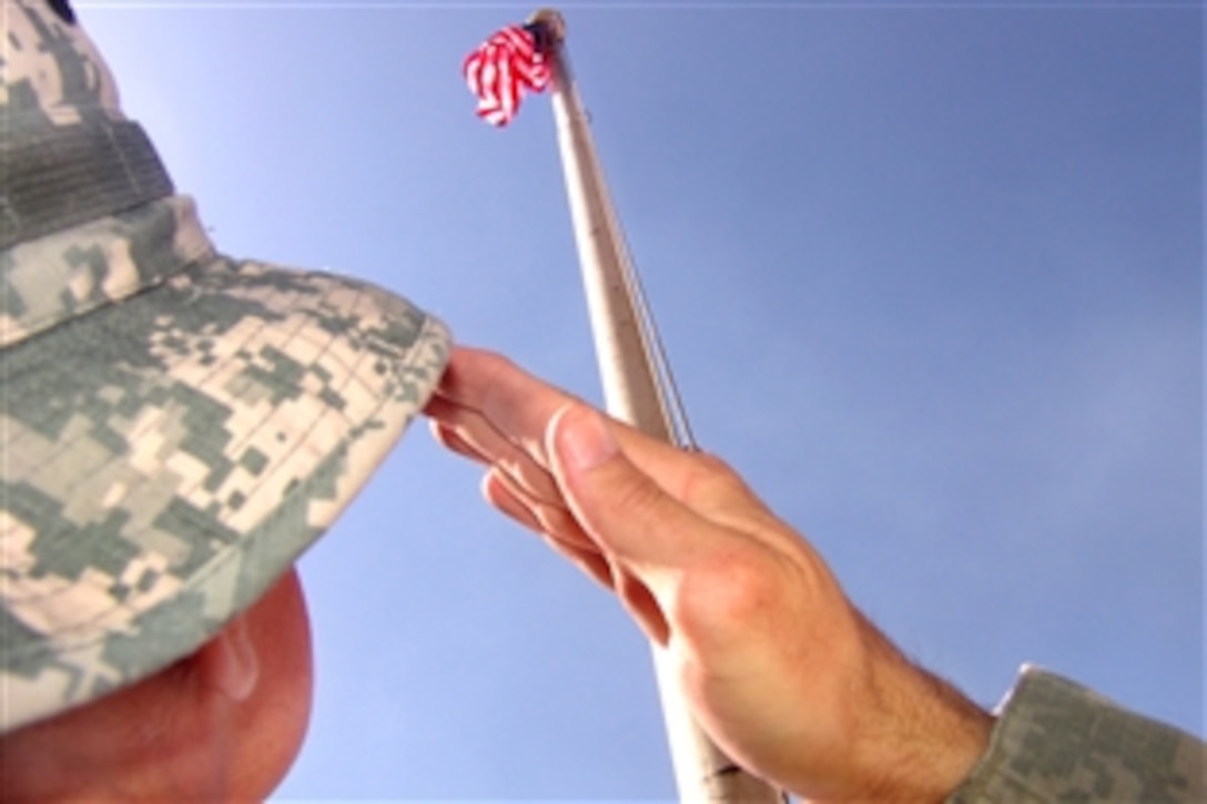 In remembrance of the 9/11 terrorist attacks, U.S. Army Maj. Marty Reigher salutes the national colors flown above Forward Operating Base Falcon, Baghdad, Sept. 11, 2009. Reigher is an information operations officer assigned to Headquarters Company, 30th Heavy Brigade Team.