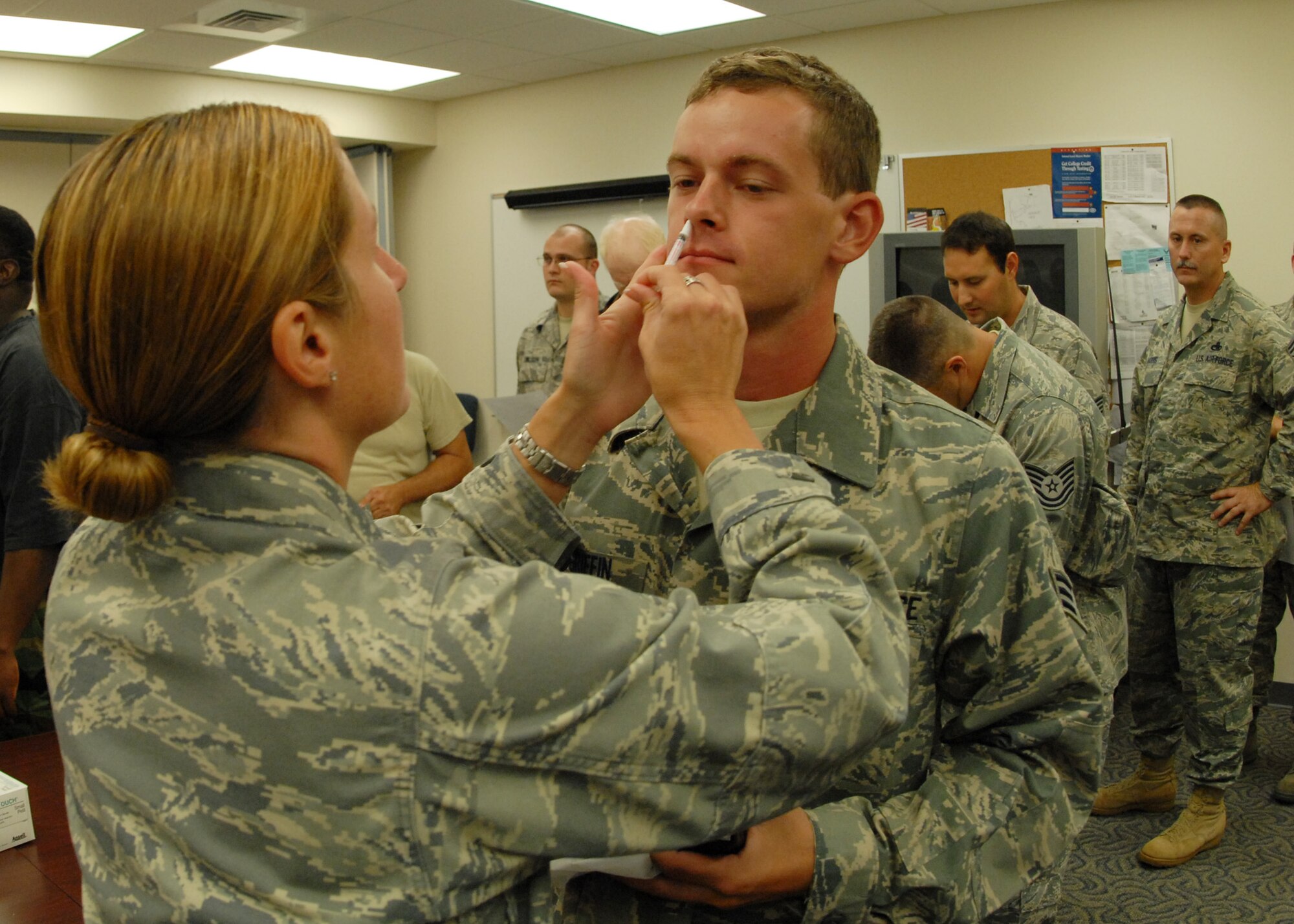 Capt. Courtney Wilson, 919th Medical Squadron, administers the flu-mist to Senior Airman John Griffin, 919th Communications Squadron, Sept. 12 while others wait to receive the vaccine at Duke Field during the UTA weekend.  (U.S. Air Force photo/Staff Sgt. Samuel King Jr.)