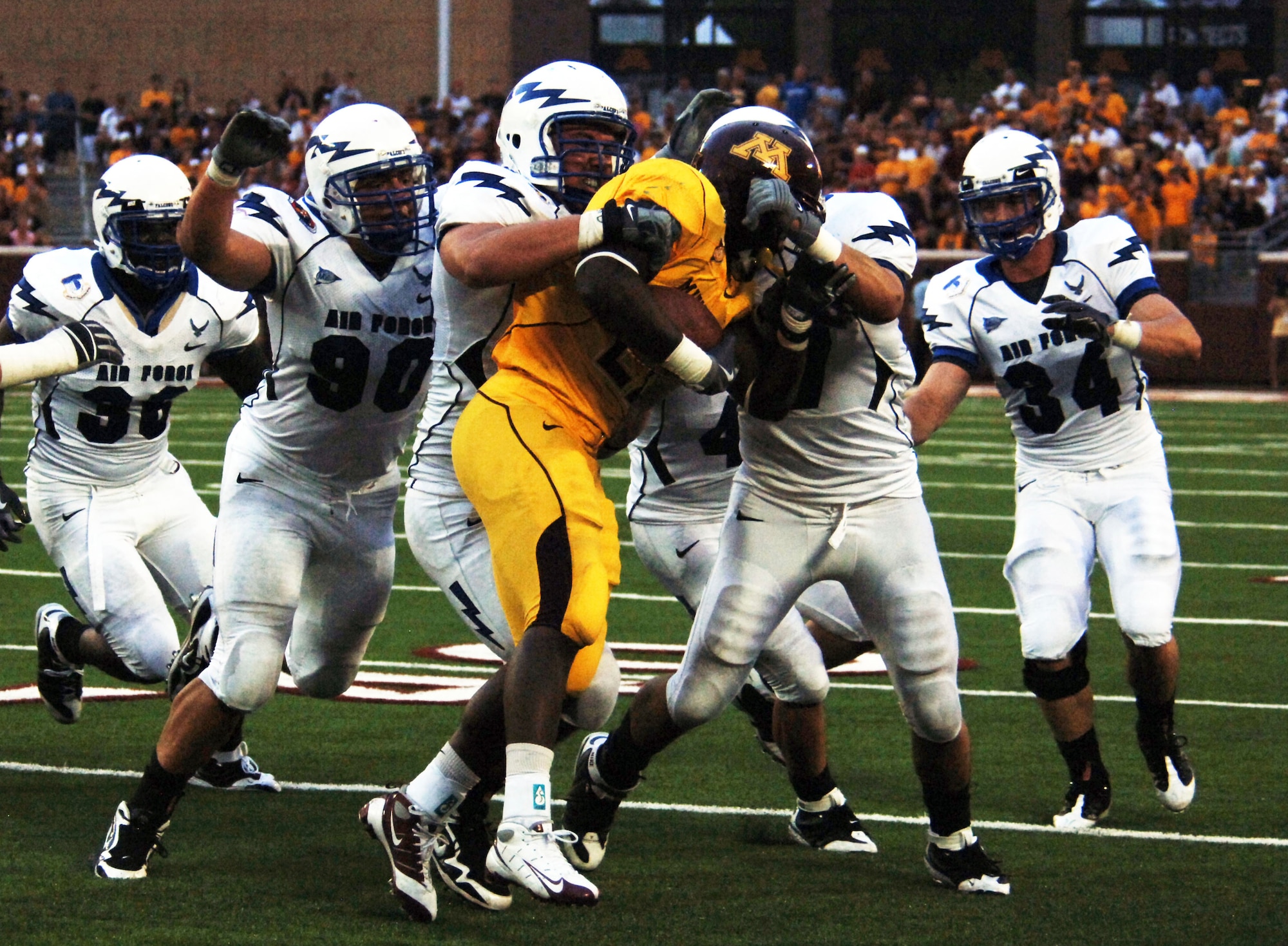 An entourage of Falcon defensive linemen wrap-up a Minnesota running back in the inaugural game at the University of Minnesota's TCF Bank Stadium Sept. 12, 2009. The pack is lead by Academy senior Ben Garland of Grand Junction, Colo. (U.S. Air Force photo/2nd Lt. Meredith Kirchoff)
