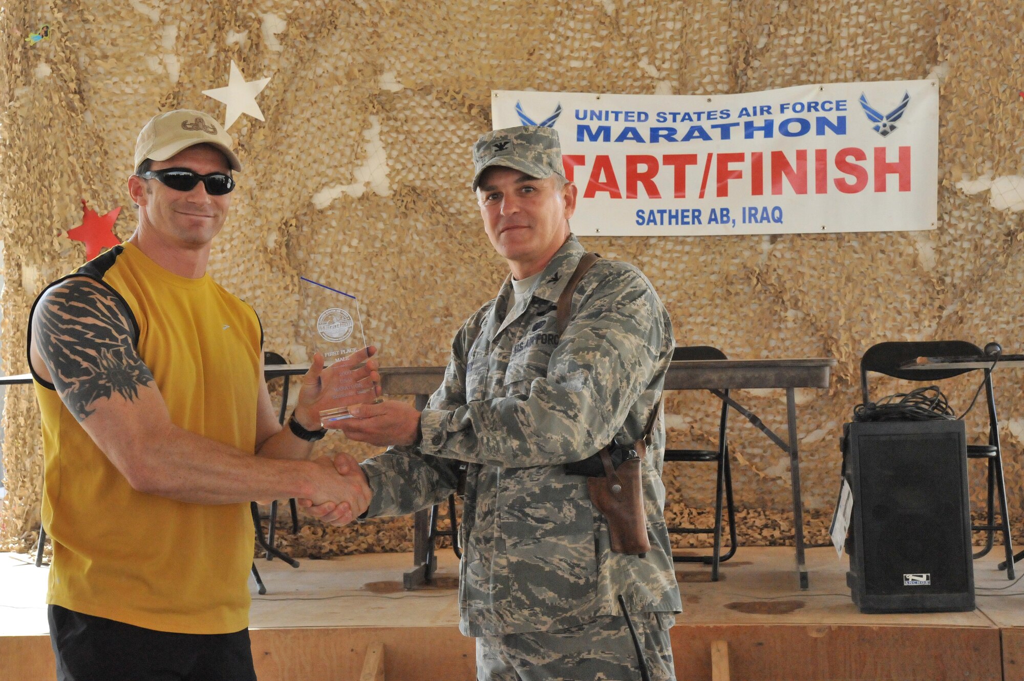 SATHER AIR BASE, Iraq -- Col. Pat Savoy, 447th Air Expeditionary Group commander, presents a first place Sather Air Force Marathon trophy to Navy Lt. j.g. Saulomon King, an explosive ordnance and disposal officer here on the Victory Base Complex.  The Lovelock, Nev. native ran the males 10-kilometer marathon in 43 minutes, 48 seconds.  (U.S. Air Force photo/Staff Sgt. Misty D. Slater)