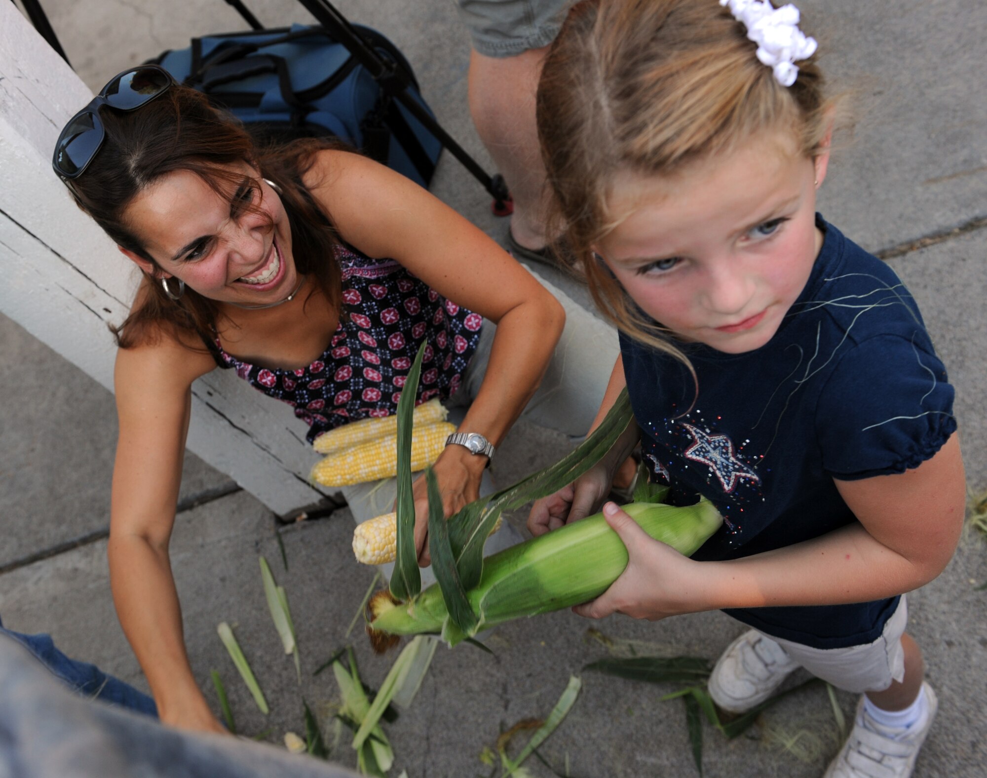 MOUNTAIN HOME AIR FORCE BASE, Idaho -- Amelia McCarthy and her mother, Heidy McCarthy, shuck corn during the 49th annual Air Force Appreciation Day corn shucking competition Sept. 11 in downtown Mountain Home. The year's festivities also included a fun run Sept. 11 and ended with the parade and free barbecue Sept. 12. AFAD began in 1962 as a way for the Mountain Home Chamber of Commerce to express their gratitude for the economic benefits the Air Force brought to the area and a way to encourage neighborly growth. (U.S. Air Force photo by Airman 1st Class Debbie Lockhart)