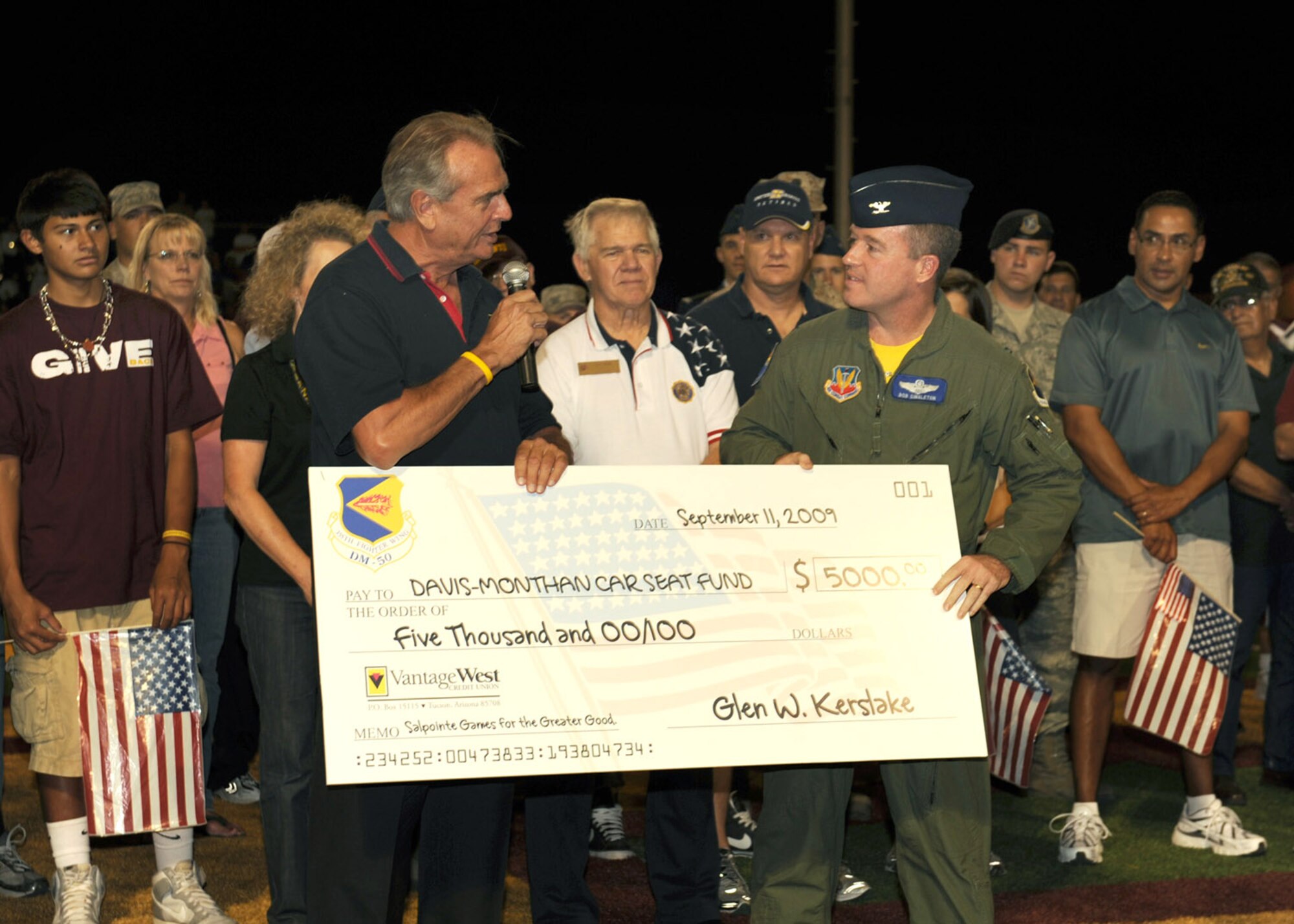 Col. Robert Singleton, 355th Fighter Wing vice commander, accepts a $5,000 check courtesy of the D-M 50, for the Davis-Monthan Car Seat Fund during Salpointe High School's varsity football game Sept. 11. Salpointe Games for the Greater Good campaign held its military appreciation night on the eighth anniversary of 9/11. (U.S. Air Force photo by Staff Sgt. Valerie Smith)