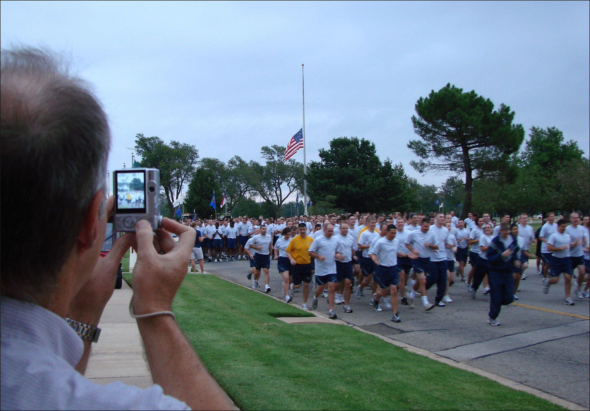 Jeff Mullin, a reporter for the Enid News & Eagle newspaper in Enid, Okla., photographs members of Team Vance participating in a 1.5 mile run on Patriot Day, Sept. 11. The run was part of the base observance to remember those who were injured or died during the terrorist attacks in the United State on Sept. 11, 2001. (U.S. Air Force photo/ Joe B. Wiles)