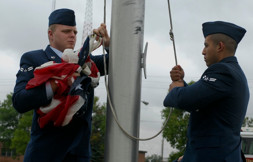 MINOT AIR FORCE BASE, N.D. -- Airman 1st Class Gene Yeater and Eric Kautz, 5th Civil Engineer Squadron firefighters, retrieve the U.S. flag during a retreat ceremony here, Sept. 11. Members from the base fire department participated in the ceremony to honor the 343 fallen firefighters of 9/11. (U.S.  Air Force Photo by Senior Airman Michael Veloz)