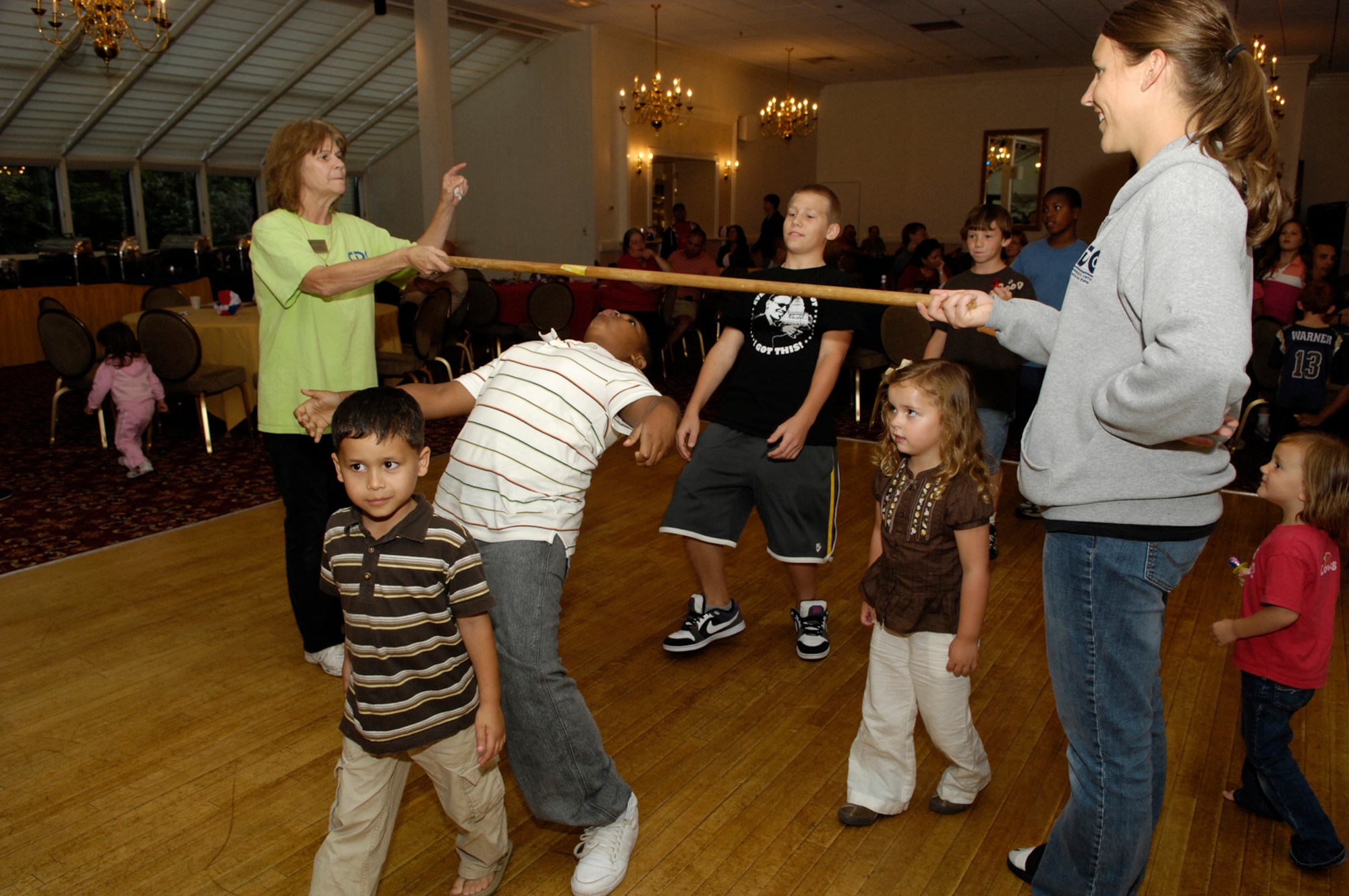 HANSCOM AIR FORCE BASE, Mass. – Rita Millar (left) and Sarah Ryals (right) both with the 66th Force Support Squadron’s Child Development Center, hold a limbo stick as children try to limbo under it during one of the games at the Back to School Blues family night at the Minuteman Club on Sept. 9. The event was free to all Club members and featured a free buffet, games, activities and giveaways.  For more information on Club membership or for a list of upcoming activities at the Minuteman Club go to www.hanscomservices.com. (U.S. Air Force photo by Mark Herlihy)