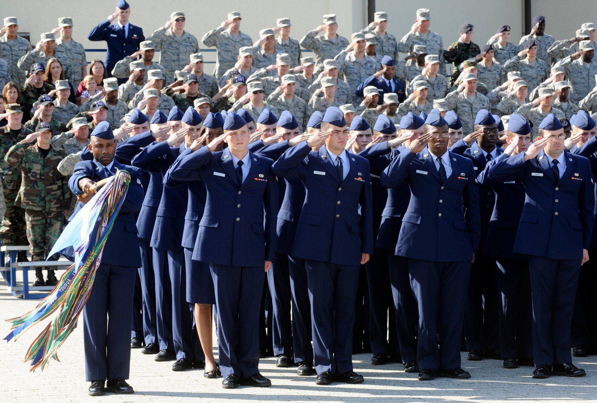 SPANGDAHLEM AIR BASE Germany – Senior Airman Jerrime Williams, 702nd Munitions Support Squadron, presents the 52nd Fighter Wing guide-on while the men and women of the 52nd Fighter Wing salute the U.S. flag as it is lowered by the base honor guard during a retreat ceremony honoring the lives lost during the Sept. 11 attacks in 2001.  Approximately 200 people attended the ceremony from the 52nd FW and tenant units.  The event was put together by the First IV. (U.S. Air Force photo/Master Sgt. Bill Gomez)