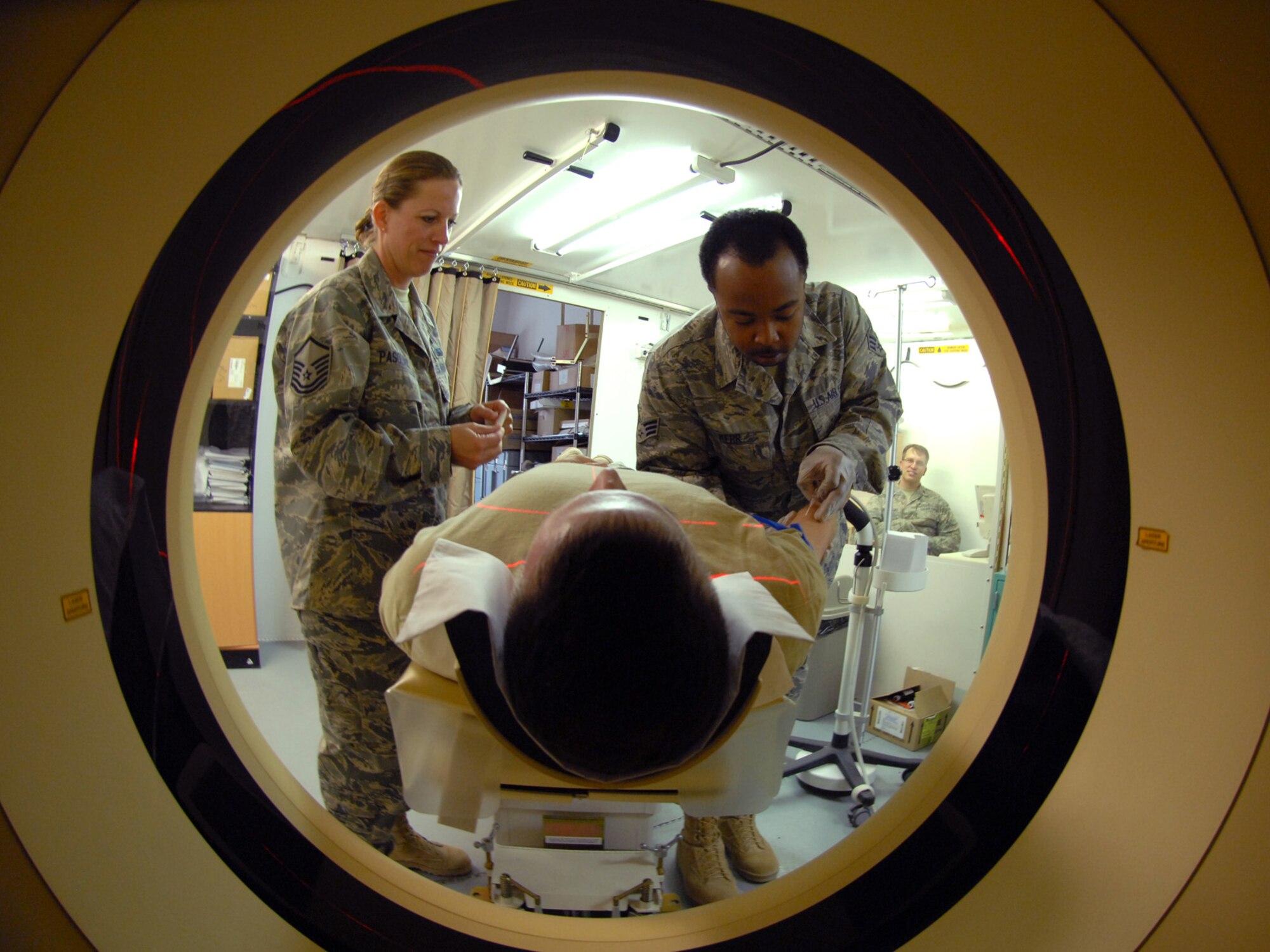 Master Sgt. Kathleen Pasquini, 379th Expeditionary Medical Group expeditionary medical operations flight chief observes a patient for allergic reaction while  Senior Airman Kenneth Kerr, 379 EMDG radiology technician administers an IV prior to a CT scan of the brain, here, Sept. 11, 2009. The EMDG provides medical care impacting missions well beyond its boundaries, helping warfighters stay in the fight in-theater.  Sergeant Pasquini is deployed from Keesler Air Force Base, Miss. Airman Kerr is deployed from Nellis Air Force Base, Nev. Both are deployed in support of Operations Iraqi Freedom and Enduring Freedom. (U.S. Air Force Photo/Tech. Sgt. Jason W. Edwards)