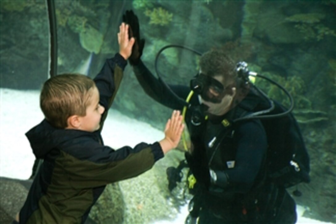 U.S. Navy Senior Chief Petty Officer Jason Sparks communicates with a young patron at Henry Doorly Zoo in Omaha, Neb., on Aug. 26, 2009.  Members of Explosive Ordnance Disposal Operation Support Unit 10 took turns diving into the zoo's aquarium throughout the day as part of Omaha Navy Week events.  Navy Weeks are designed to show Americans the investment they have made in their Navy and increase awareness in cities that do not have a significant Navy presence.  