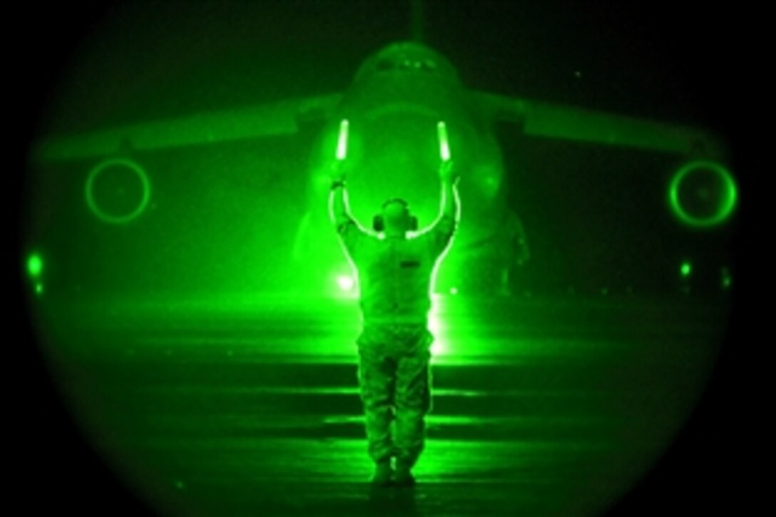 As seen through a night-vision device, U.S. Air Force Master Sgt. Richard Biasi marshals a C-5M Super Galaxy before it takes off from Dover Air Base, Del., Sept. 13, 2009. An aircrew of active duty and Air Force Reserve members flew the C-5M, named "The Spirit of Normandy," on a mission that unofficially set 41 records in a single flight Sept. 13. The certified results are expected to be released in about a month.