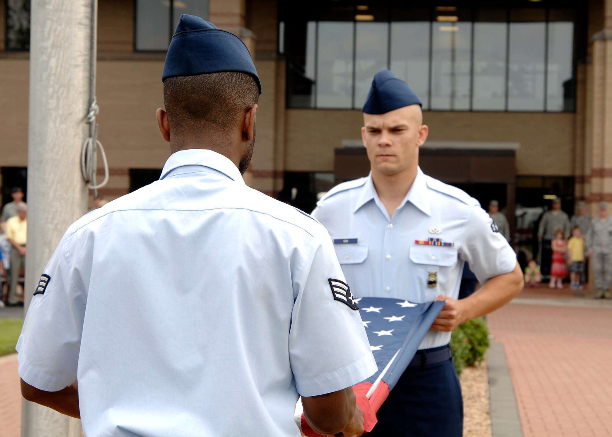 Airman 1st Class Derald Cox, 22nd Civil Engineer Squadron, and Senior Airman Antoine Steele (on left), 22nd Medical Support Squadron, fold the U.S. flag, Sept. 11, 2009, during a Patriot Day retreat ceremony at McConnell Air Force Base, Kan. Congressional public law states all U.S departments, agencies and instrumentalities should display the flag half-staff on Patriot Day. (U.S. Air Force photo/Senior Airman Anthony Mejia)