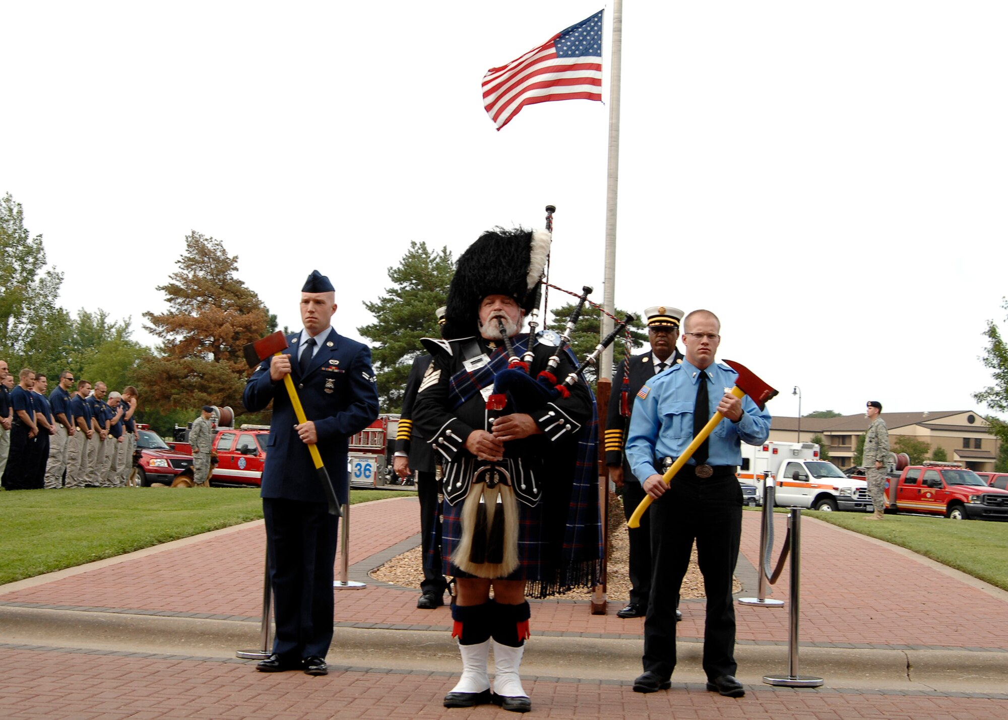 Airman 1st Class Matthew Keenan and Mr. Christopher Muriset (on right) firefighters from the 22nd Civil Engineer Squadron, flank William McCollum, Caledonian Pipes and Drums bagpiper, while he plays “Amazing Grace,” at a Patriot Day retreat ceremony, Sept. 11, 2009, at McConnell Air Force Base, Kan. (U.S. Air Force photo/Senior Airman Anthony Mejia)