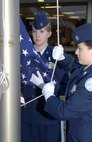 MINOT, N.D. -- Cadet Major Elizabeth Stahl, Cadet Corps squadron ND20021 commander, leads Cadet Capt. Sara Fundingsland, during the flag detail for a ceremony remembering the lives lost and commemorating the heroism and comradery in the Sept. 11, 2001 terrorist attacks at the Magic City Campus High School Sept. 11 here. (U.S. Air Force Photo by Airman 1st Class Benjamin Stratton)