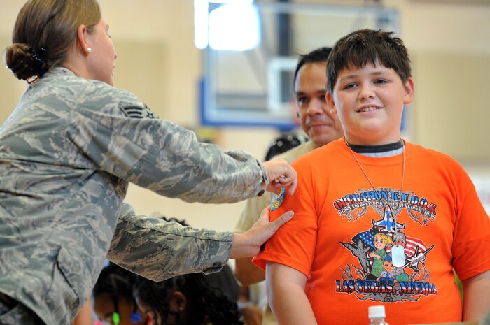 NELLIS AIR FORCE BASE, Nev.,-- Stephen Cibo Jr. gets a sticker for a simulated shot from Senior Airman Elena Ramirez, from the 99th Medical Group immunizations clinic, while participating in Kids Understanding of Deployment Operations (KUDO). KUDO is a mock deployment created to help military children understand what their parents experience. Hundreds of military children participated in KUDO at the Nellis' Youth Center, Sept. 12. (U.S. Air Force photo by Tech. Sgt. Michael R. Holzworth)