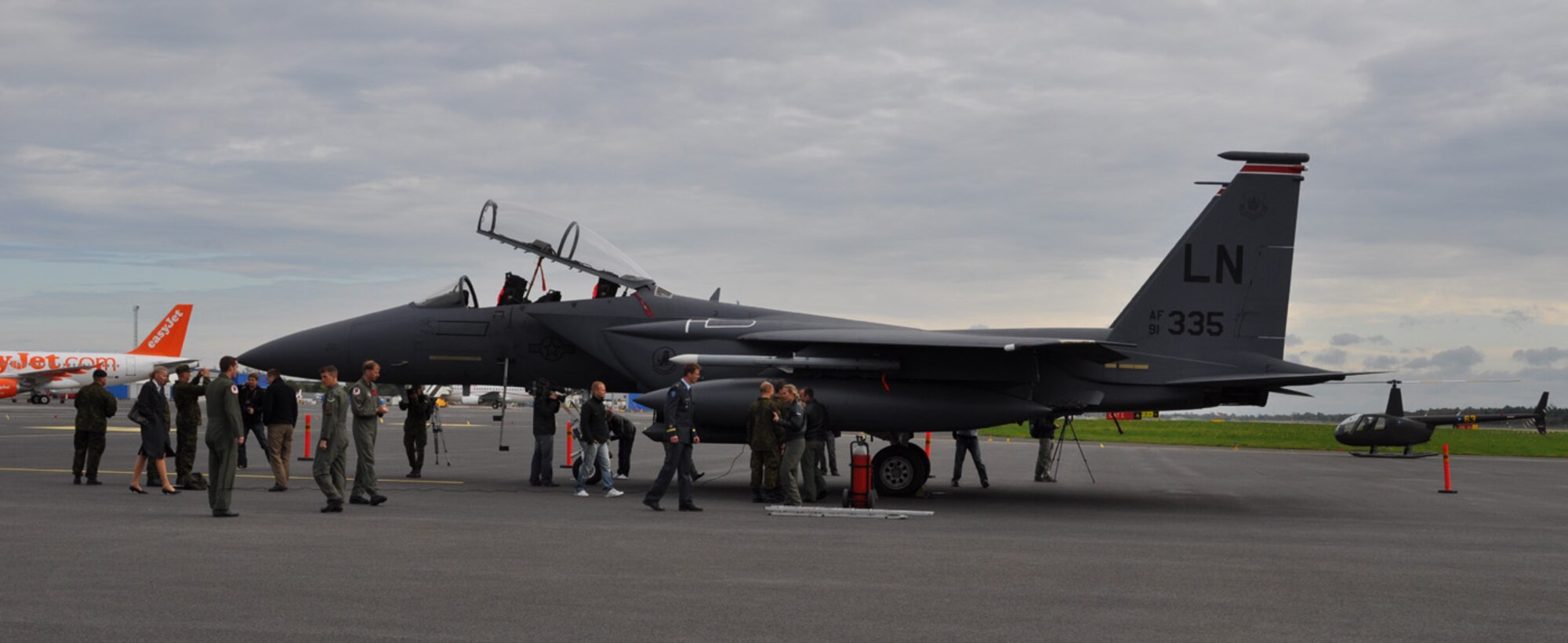An F-15E fighter jet from the 494th Fighter Squadron sits on the ramp at Tallinn International Airport, Estonia, after flying from its home base, RAF Lakenheath, United Kingdom, and performing a two hour training mission with Estonia forward air controllers (FAC), known as joint terminal attack controllers to the U.S. military. The aircrew prepares to be shuttled in an Estonian Robinson R44 helicopter, in the background, to the training area to debrief the FAC's. The purpose of the training is to enhance the abilities of Estonian FAC's and ground commanders in employing NATO air strike assets. (U.S Air Force photo/Lt. Col. Jim Parker)