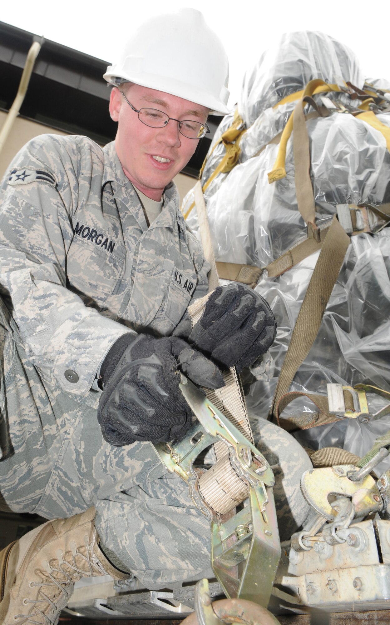 Airman 1st Class Scott Morgan, member of the 1st Combat Communications Squadron, tightens down a cargo strap in order to securing a pallet in preparation for a vehicle convoy from Ramstein Air Base Germany to Aviano Air Base Italy.  The convoy consists of seven trucks carrying approximately 10 tons of equipment. (U.S. Air Force photo by Tech Sgt. Sean Mateo White)