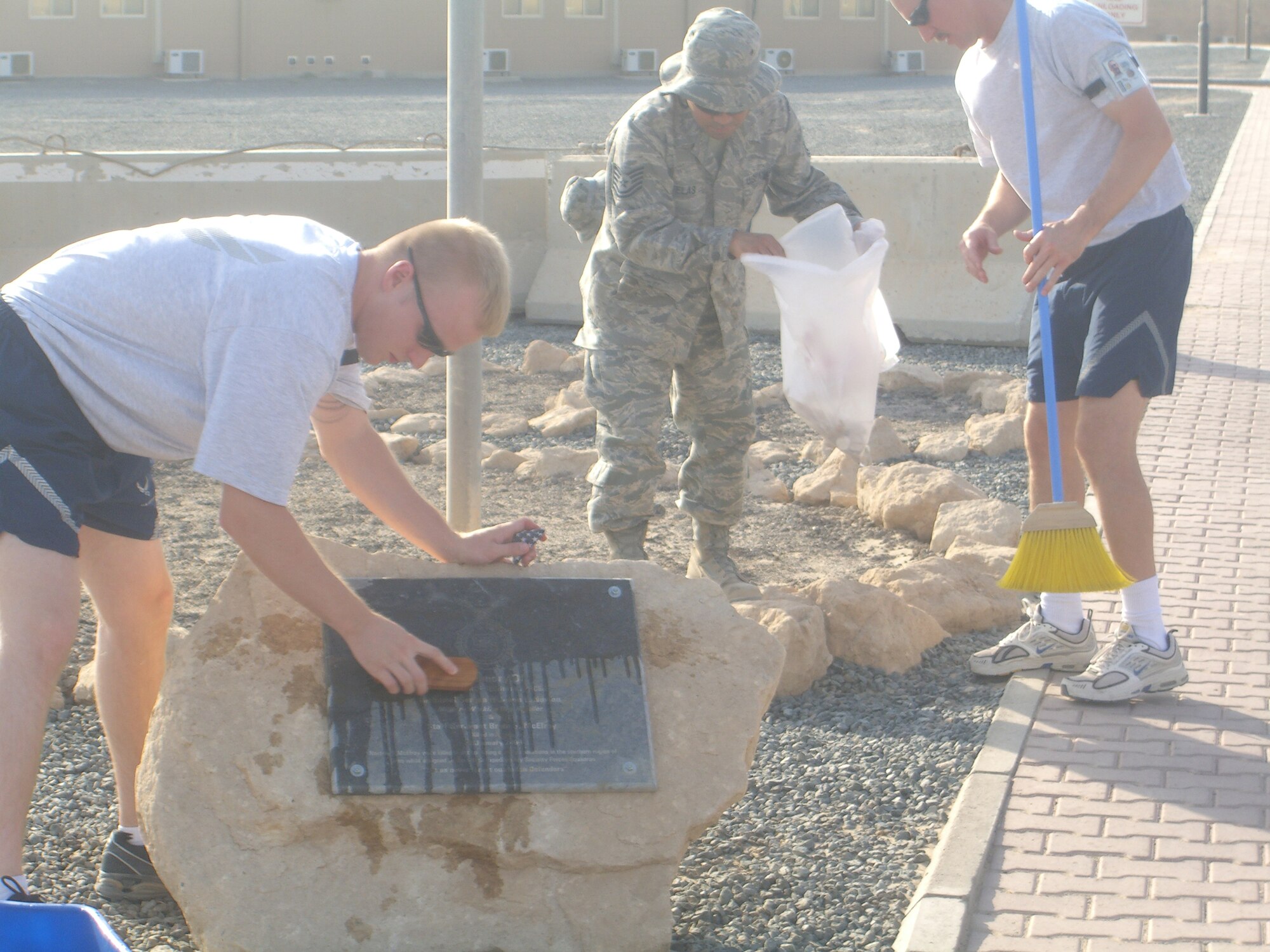 SOUTHWEST ASIA – (left to right) Senior Master Sgt. Joseph Samulowitz; Tech. Sgt. Henry Ruelas and Master Sgt. Chris Roybal, all from the 386th Expeditionary Communications Squadron, clean up one of eight different memorials and monuments located on base Sept 6. The team spent time at each site scrubbing away dirt and removing any trash they found. (U.S. Air Force/Courtesy photo)