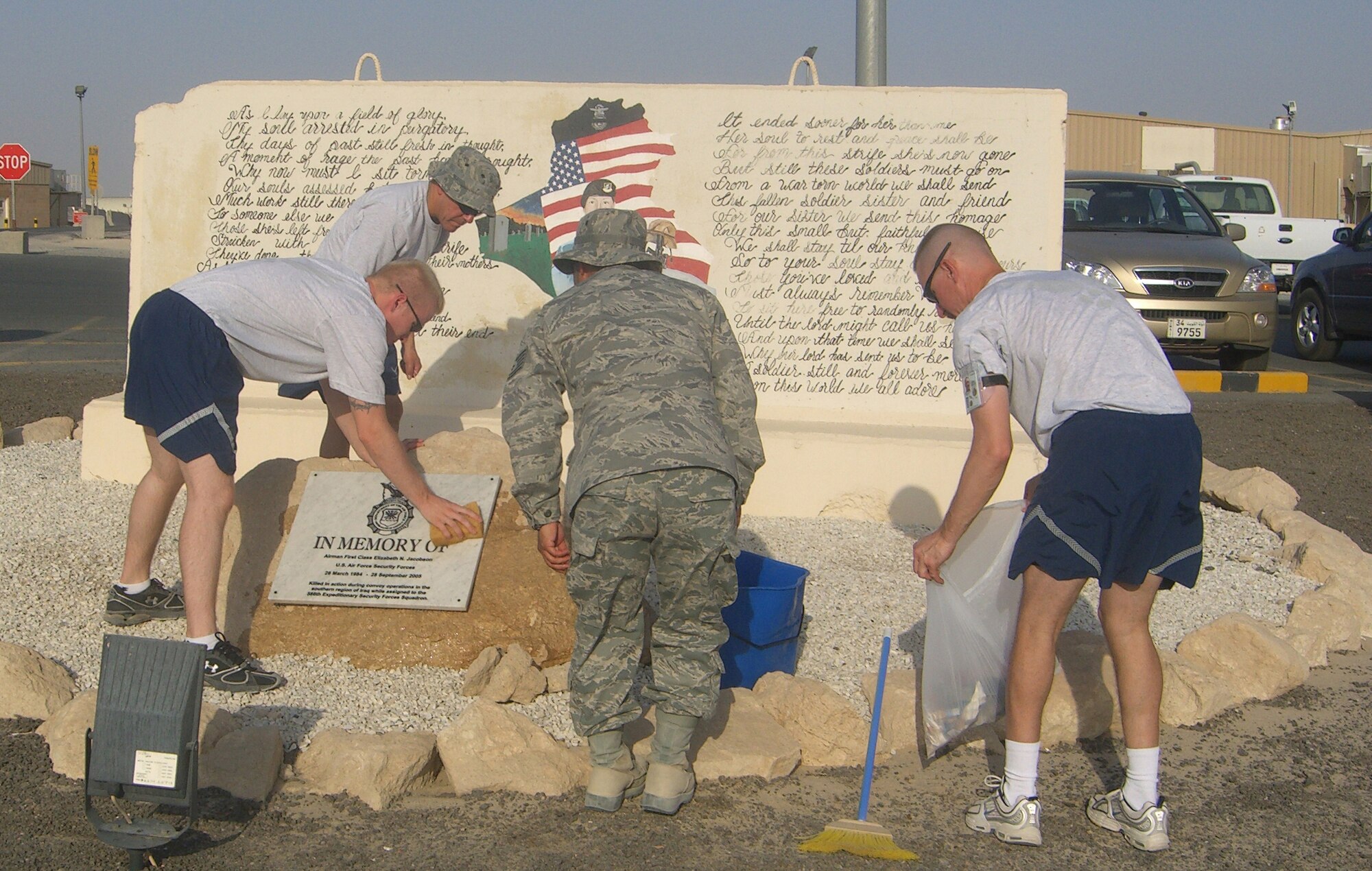 SOUTHWEST ASIA -- Tech. Sgt. Henry Ruelas (center), 386th Expeditionary Communications Squadron, and several Airmen from the 386th ECS clean a memorial dedicated to Airman 1st Class Elizabeth Jacobson. Airman Jacobson was killed Sept. 28, 2005 while providing convoy security near Camp Bucca, Iraq, when her vehicle was hit by an improvised explosive device. (U.S. Air Force/Courtesy photo)