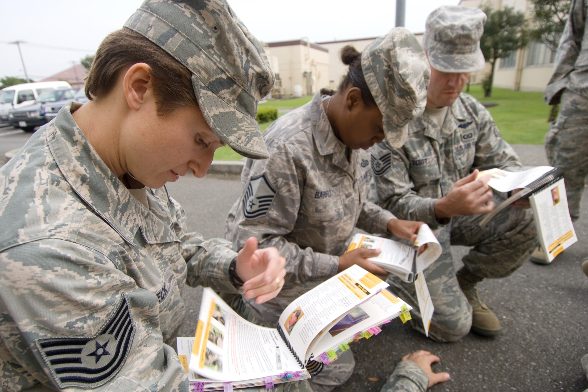 YOKOTA AIR BASE, Japan -- Tech. Sgt. Claire Beck, 374th Comptroller Squadron, (left) and fellow 374th Airlift Wing staff agency Airmen check their Airman's Manuals for self-aide, buddy care techniques during Ability to Survive and Operate training recently. ATSO knowledge will be an area of emphasis during the wing's upcoming Operational Readiness Inspection. (U.S. Air Force photo/Osakabe Yasuo)
