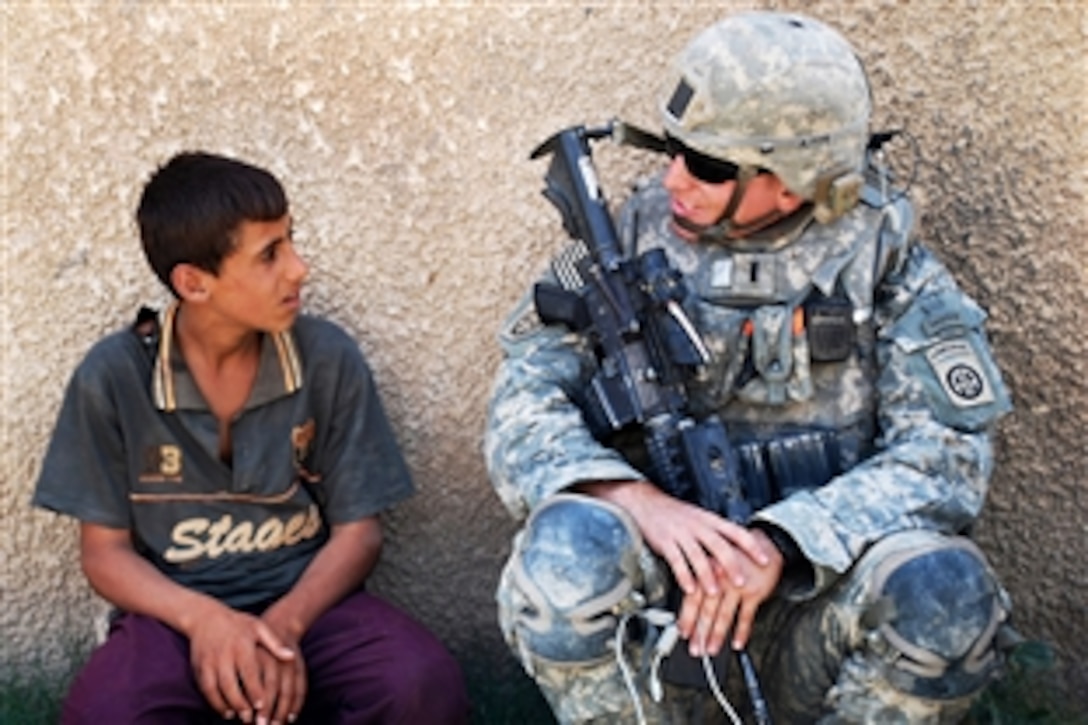 U.S. Army 1st Lt. Jeffrey Wismann speaks to an Iraqi boy as his Iraqi army partners enter a nearby home during a combined foot patrol Sept. 13, 2009, in the town of Salman Pak southeast of Baghdad, Iraq, Sept. 13, 2009. Wismann is assigned to the 82nd Airborne Division's Company B, 1st Battalion, 505th Parachute Infantry Regiment, 3rd Brigade Combat Team.