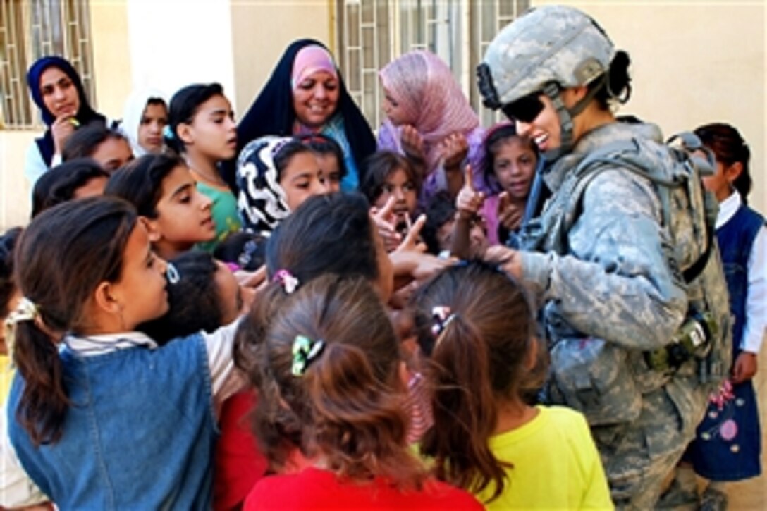 U.S. Army Spc. Ikram Mansori greets a group of Iraqi girls after giving them toys during a combined humanitarian assistance mission at the Gulgamesh Elementary School in the town of Salman Pak, Iraq, Sept. 13, 2009. Mansori is assigned to the 82nd Airborne Division's Company B, 1st Battalion, 505th Parachute Infantry Regiment, 3rd Brigade Combat Team.