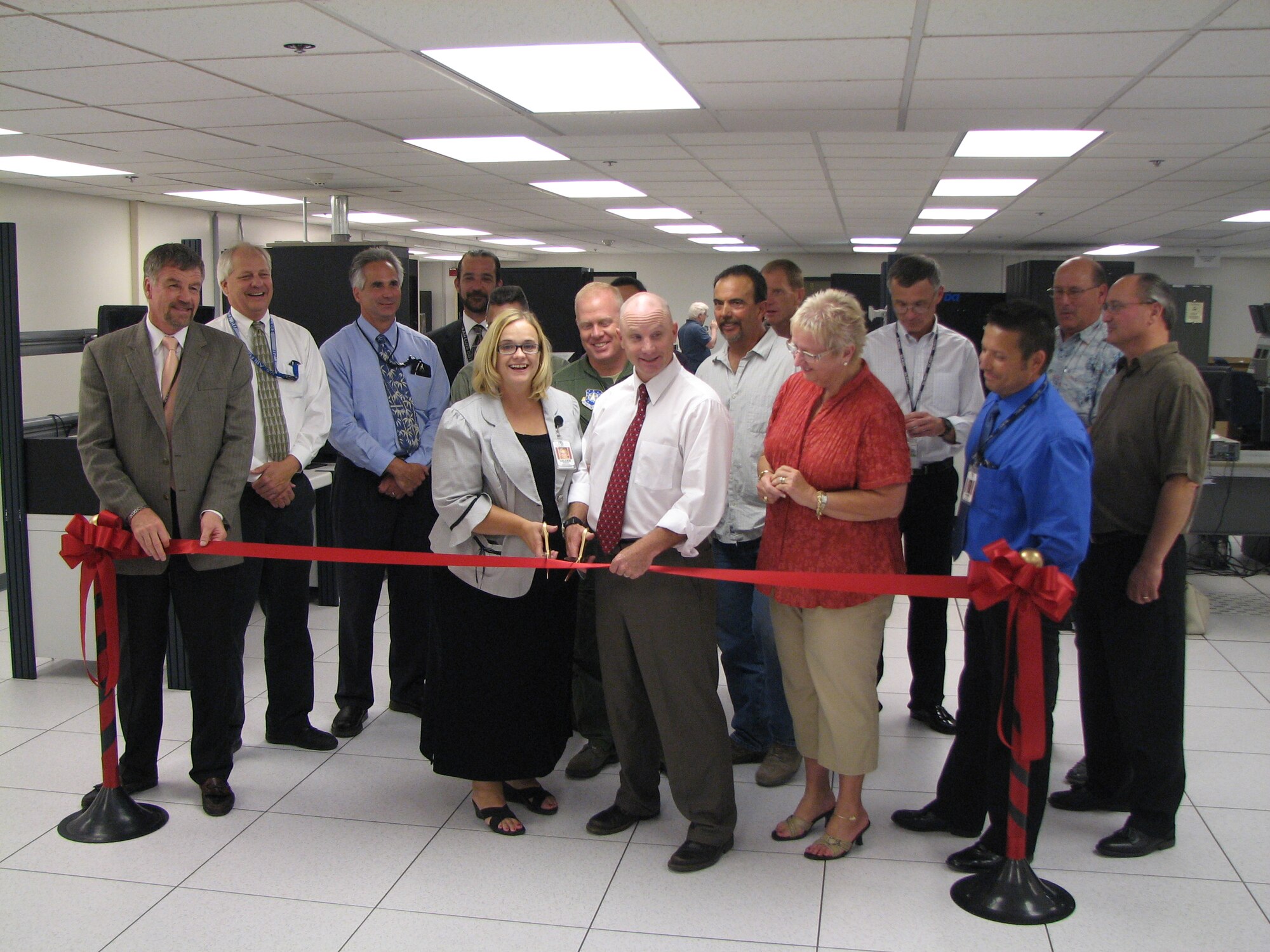 VANDENBERG AIR FORCE BASE, Calif. --  Getting ready to the cut the ribbon, Valarie Robison, who works with the ITT-Spacelift Range Systems Contract, and Dave Brown, with the Space Launch Group, both in the center, celebrate the completion of the Western Range Software Maintenance Facility expansion project here Aug. 27. The main function of the Software Maintenance Facility is to reproduce an operational systems environment within a closed network to provide dedicated platforms that allow for the evolution and sustainment of Western Range systems. (U.S. Air Force photo)