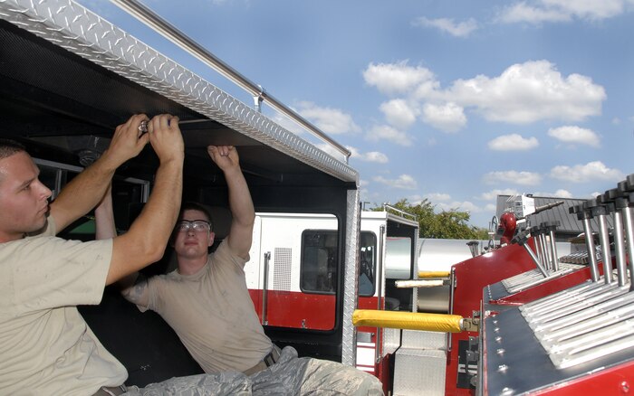 Staff Sgt. Carl Ellis and Airman 1st Class Erik Bickmore install an overhead dome light assembly in the rear cab of a P-24 structural fire truck at the fire department here Sept. 16. The dome light was reported cracked and unserviceable to the vehicle maintenance section at the fire department, which resulted in removal and replacement of the entire assembly. Sergeant Ellis is a fire truck maintenance journeyman and Airman Bickmore is a special vehicle maintainer, both are with the 437th Logistics Readiness Squadron. (U.S. Air Force photo/Staff Sgt. Daniel Bowles)