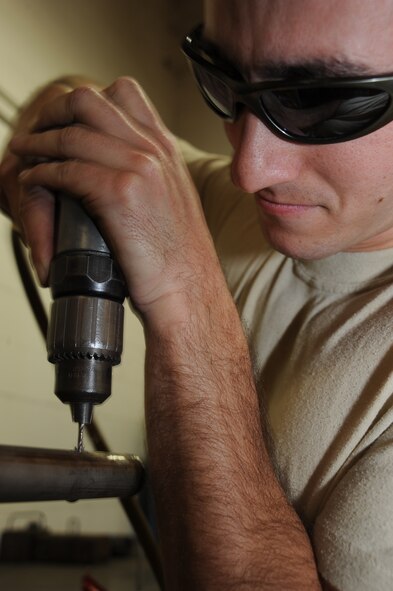 Senior Airman Justin Gadell, 22nd Maintenance Squadron Fabrication Flight, drills a hole in a hatch barrier for a KC-135 back door frame, Sept. 14, 2009, at McConnell Air Force Base, Kan. Hatch barriers prevent things from falling out of aircraft when doors are absent. (U.S.  Air Force photo/Tech. Sgt. Chyrece Campbell)