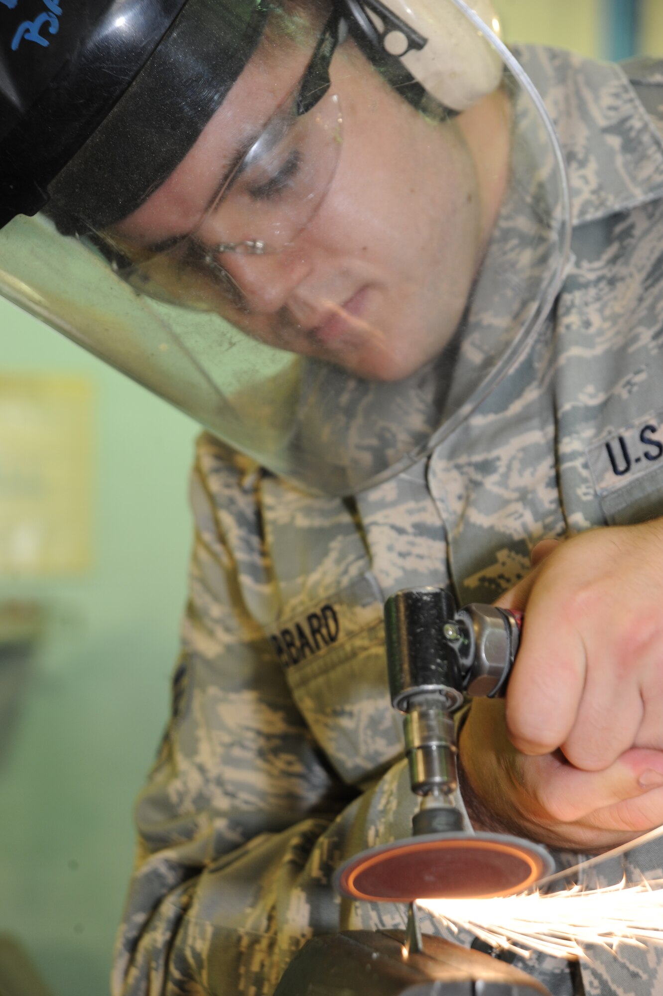 Senior Airman Jonathan Hubbard, 22nd Maintenance Squadron Fabrication Flight, conducts a spark test on a piece of metal to determine its type, Sept. 14, 2009, at McConnell Air Force Base, Kan. To perform the test, he sanded the metal and evaluated the color of sparks it produced.  Each metal gives off a unique color of spark. (U.S. Air Force photo/Tech. Sgt. Chyrece Campbell)