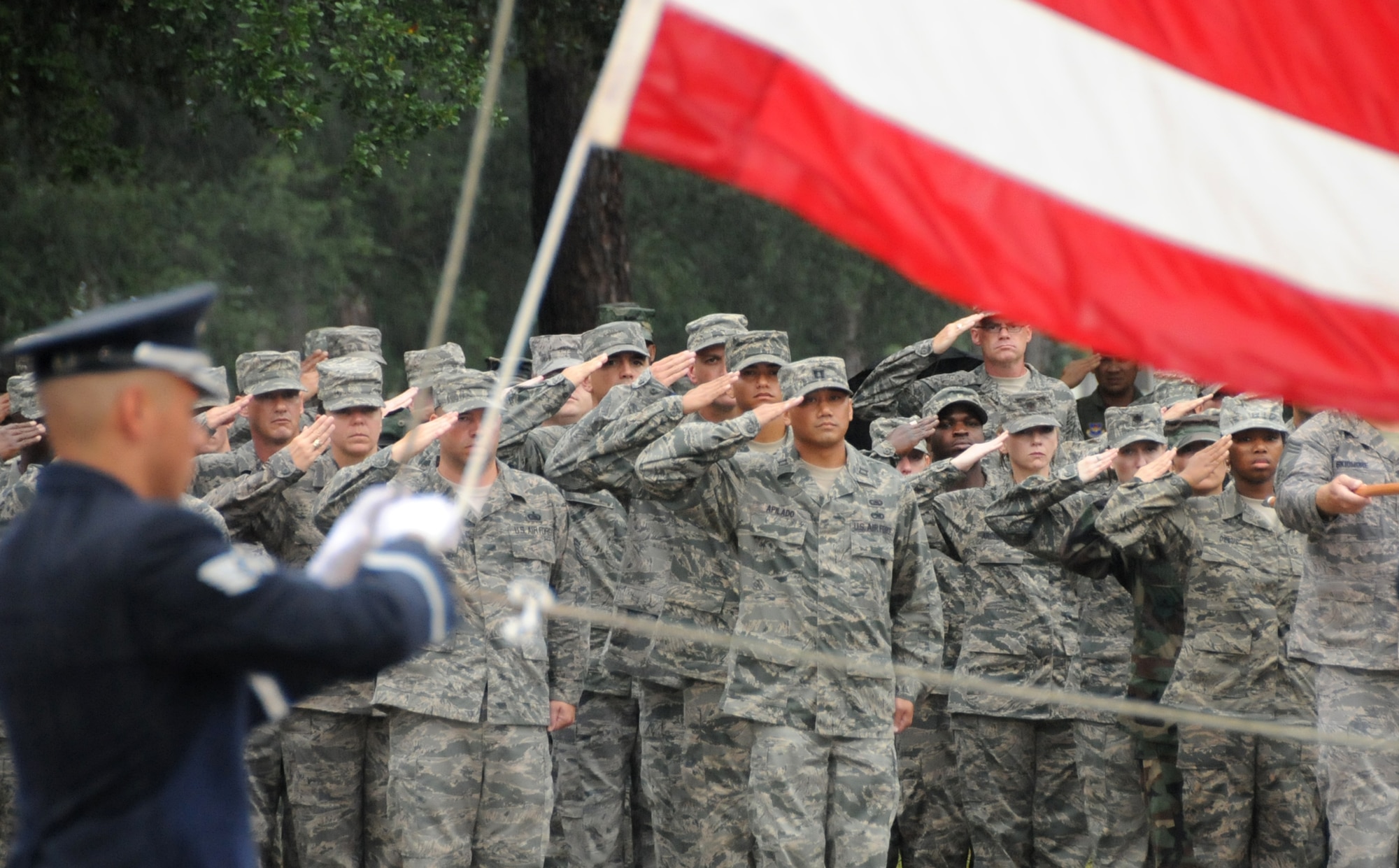 Staff Sgt. Jose Ramos from the Keesler Honor Guard lowers the flag at the retreat ceremony as Keesler members salute.  (U.S. Air Force photo by Kemberly Groue)