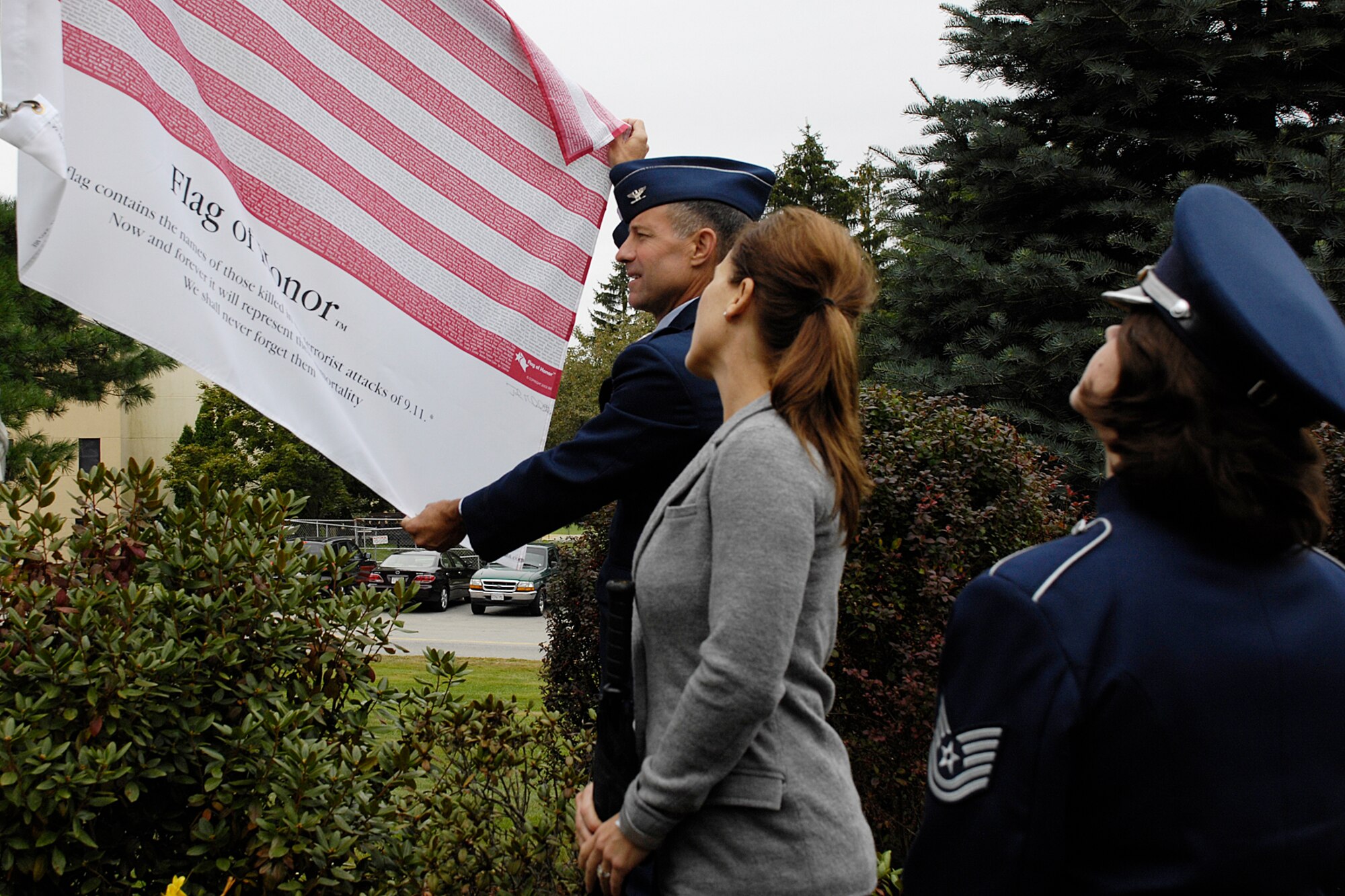 HANSCOM AIR FORCE BASE, Mass. - Col. David Orr, 66th Air Base Wing commander, holds open the Flag of Honor during the Sept. 11 remembrance ceremony at Hanscom’s POW/MIA Memorial Park. Written on the flag is “This flag contains the names of those killed in the terrorist attacks of 9/11. Now and forever it will represent their immortality. We shall never forget them.” The Flag of Honor was created by John Michelotti after he recuperated from emergency bypass surgery.  Faced with his mortality, he became sensitive to the fate of the victims and wanted to honor their individual lives. (U.S. Air Force photo by Linda LaBonte Britt)