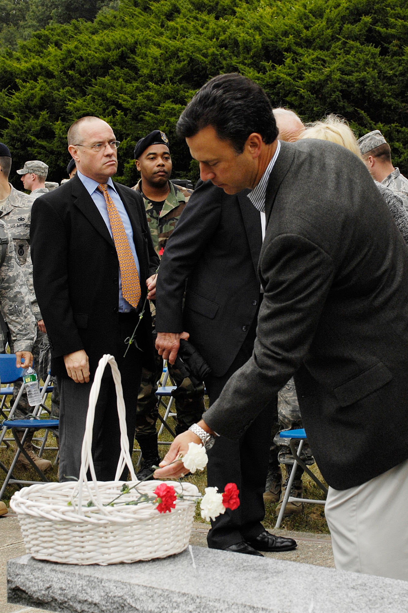 HANSCOM AIR FORCE BASE, Mass. - In front of the rock that bears the words “All gave some, some gave all,” Jonathan Elias, 66th Air Base Wing honorary commander and anchorman for WBZ Television in Boston, drops a carnation into a basket, symbolizing the ultimate sacrifice made by 2,974 individuals on Sept. 11, 2001. (U.S. Air Force photo by Linda LaBonte Britt)