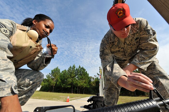 Senior Airman Tremaine Wright-Aklin observes Staff Sgt. Anthony Waldon adjusting the front sights of a M-16A2 rifle at Naval Weapons Station Charleston, S.C., Sept. 10. The 437th Security Forces Squadron combat arms instructors are responsible for inspecting and maintaining more than 6,000 weapons annually. Airman Wright-Aklin is a readiness spare package specialist with the 437th Logistics Readiness Squadron and Sergeant Waldon is a combat arms instructor with the 437 SFS. (U.S. Air Force photo/ James M. Bowman)