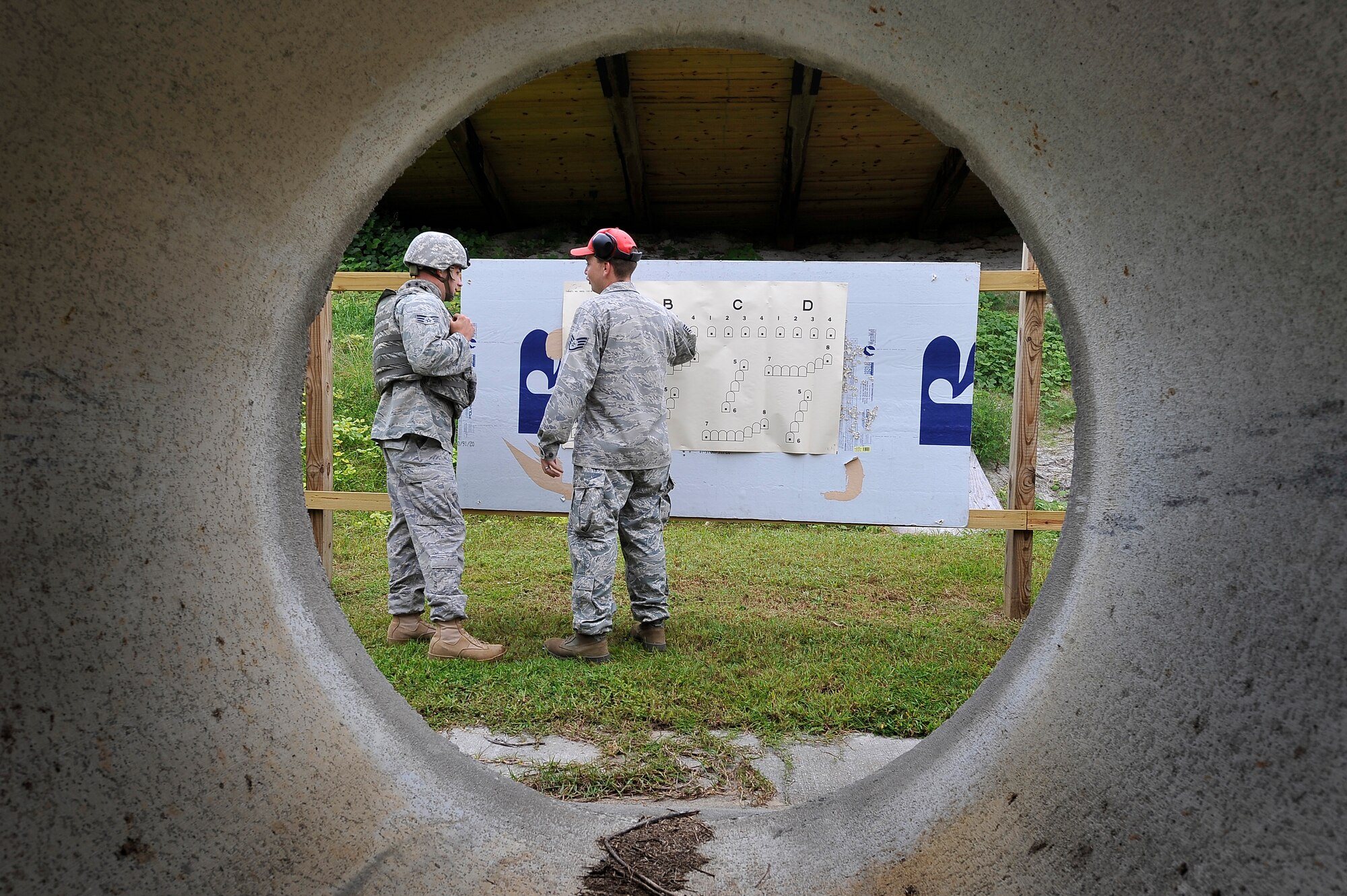 Staff Sgt. Shaun Ferguson critiques Senior Airman Jonathan Garrett's aim after shooting an M-249 automatic rifle at Charleston AFB Sept. 10. The 437th Security Forces Squadron combat arms instructors train more than 3,200 students on 10 different weapons systems. Sergeant Ferguson is a combat arms instructor and Airman Garrett is a security forces member. (U.S. Air Force photo/James M. Bowman)