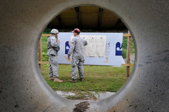 Staff Sgt. Shaun Ferguson critiques Senior Airman Jonathan Garrett's aim after shooting an M-249 automatic rifle at Charleston AFB Sept. 10. The 437th Security Forces Squadron combat arms instructors train more than 3,200 students on 10 different weapons systems. Sergeant Ferguson is a combat arms instructor and Airman Garrett is a security forces member. (U.S. Air Force photo/James M. Bowman)