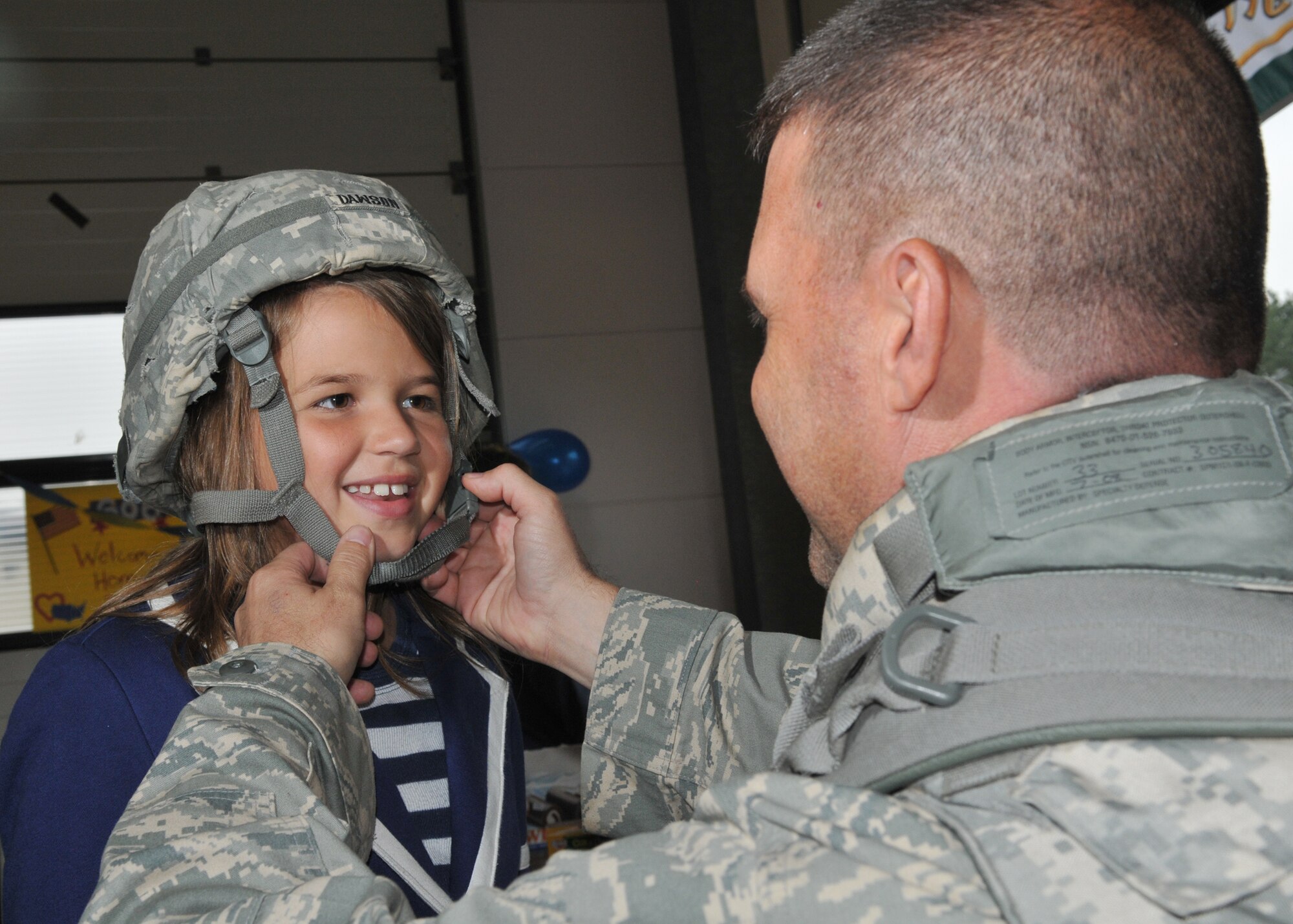 SPANGDAHLEM AIR BASE, Germany – Lt. Col. Gary Dawson, 606th Air Control Squadron director of operations, puts his helmet on his daughter Katie after returning from a four-month deployment to Kandahar, Afghanistan, Sept. 16.  About 60 members of the 606th ACS operated radar and communication for command and control for the 71st Expeditionary Air Control Squadron.  The unit also deployed 300 short tons of equipment to support air battle management operations and more than 13,000 sorties.  Approximately 30 other 606th ACS members also returned from a four-month deployment to southwest Asia in support of the 73rd EACS.  (U.S. Air Force photo/Airman 1st Class Nick Wilson)