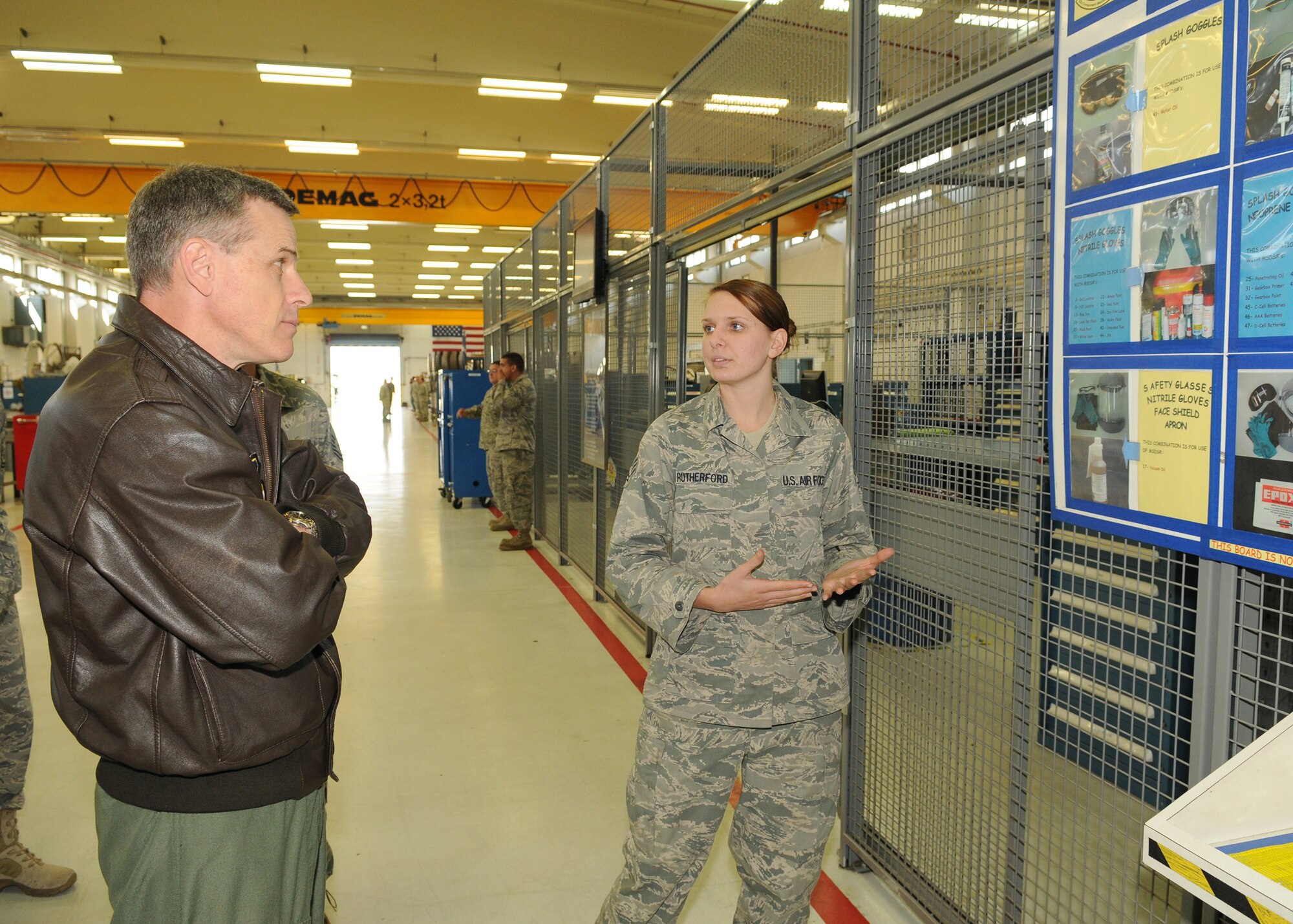 SPANGDAHLEM AIR BASE, Germany -- Senior Airman Erin Rutherford, 52nd Component Maintenance Squadron, explains to Maj. Gen. William Chambers, U.S. Air Forces in Europe vice commander, the  material safety data sheet safety poster she created during General Chamber’s first visit here Sept. 15. The safety board improves safety because pictures correspond with the chemical making them easier to identify. (U.S. Air Force photo/Airman 1st Class Nathanael Callon)