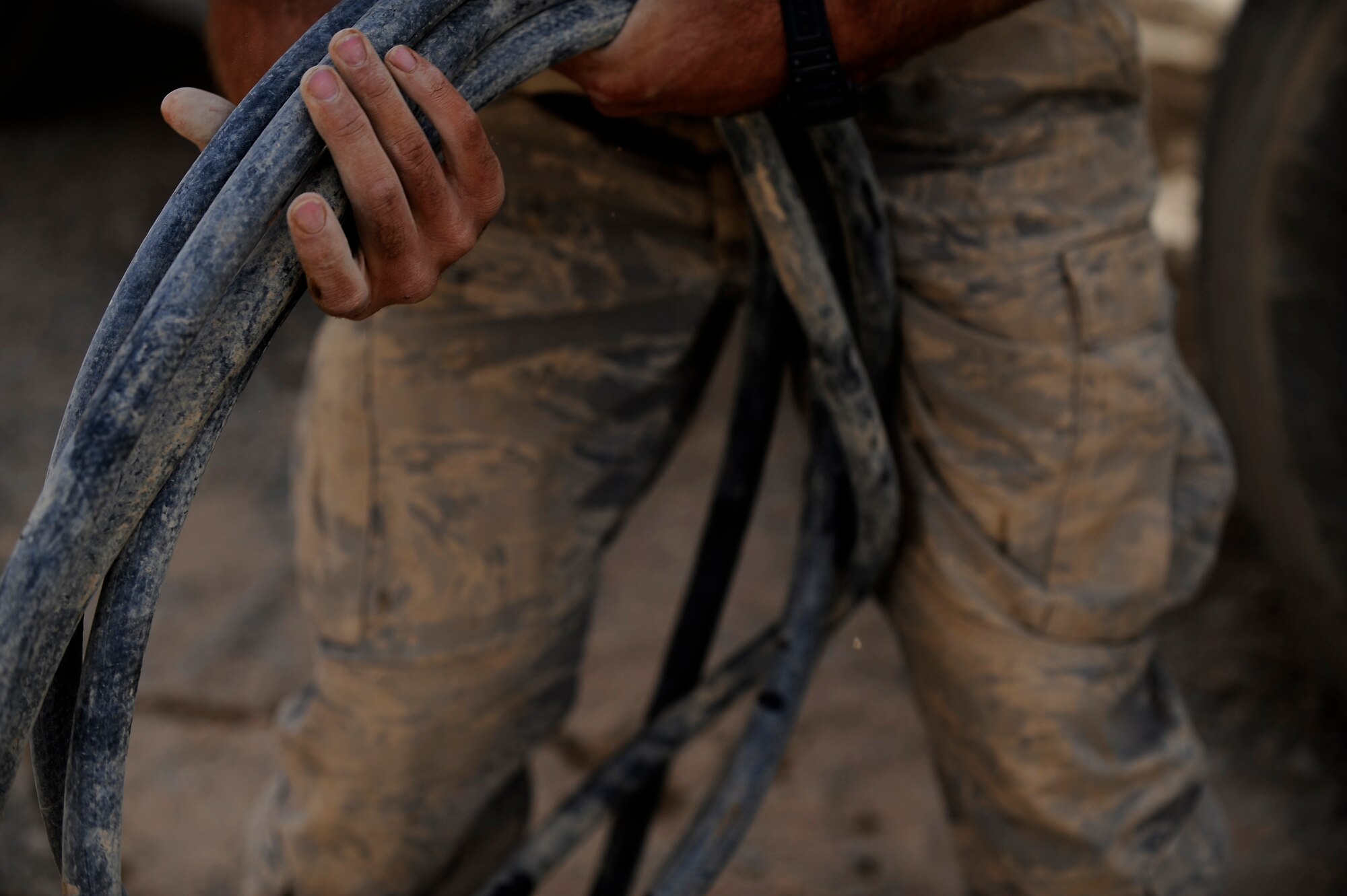 An Airman assigned to the 809th Expeditionary Red Horse Squadron, 1st Expeditionary Red Horse Group, carries a hose after wetting down some concrete  Sept. 10., Forward Operating Base Dwyer, Afghanistan (U.S. Air Force Photo/Staff Sgt. Shawn Weismiller)