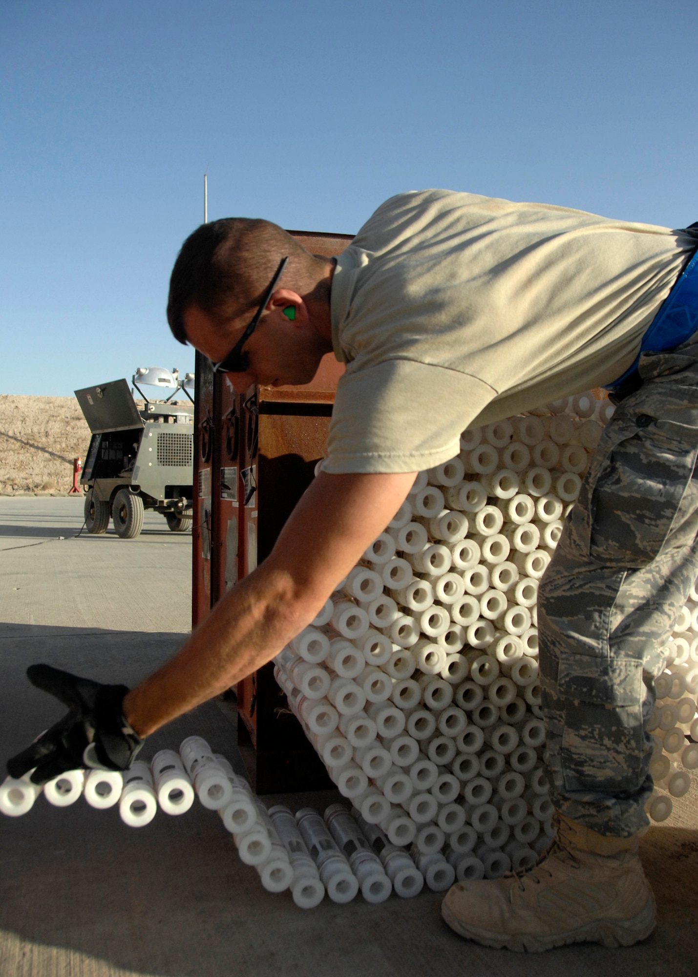 Airman 1st Class Zachariah Grube rolls an empty string of 30mm casings after connecting unused rounds with a fresh string at the M4 pad in the Army Ammunition Supply point here, Sept. 15, 2009. Using the a GFU-7 control board and a GFU-8 ammunition loading assembly Airmen link left over 30mm rounds with a new string. Airman Grube is a Munitions Crew Member with the 451st Expeditionary Maintenance Squadron from Davis-Monthan Air Force base and hails from Diamond, Mo. (U.S. Air Force photo/Senior Airman Timothy Taylor)