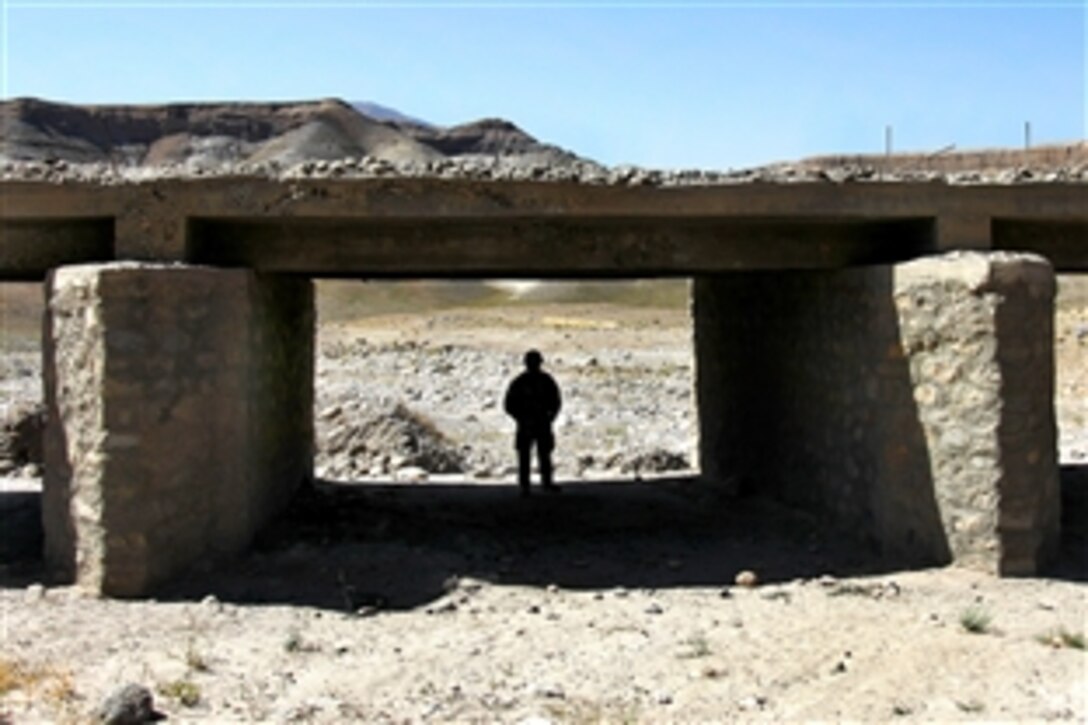 A U.S. servicemember, part of an effort led by the Kapisa-Parwan Provincial Reconstruction Team to survey Afghan project sites,  inspects a bridge in Mahmood Rahqi, Afghanistan, Sept. 9, 2009.