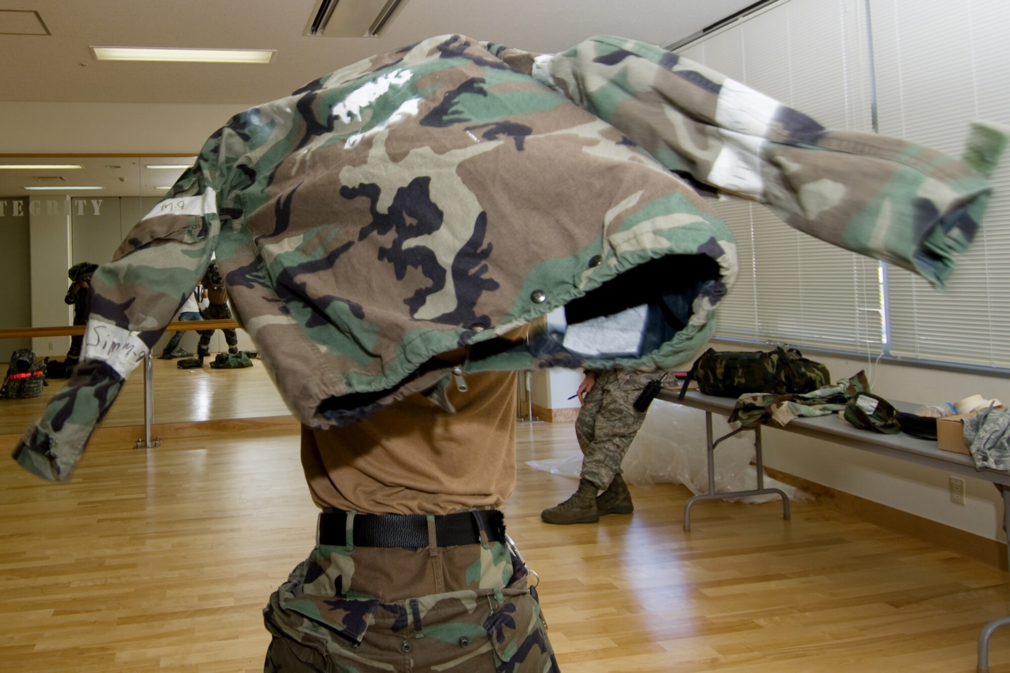YOKOTA AIR BASE, Japan -- Airman 1st Class Dante Money, 374th Security Forces Squadron, quickly dons his chemical protective overgarment during an Ability to Survive and Operate Rodeo PAR team competition Sept. 17 at the Taiyo Community Center. Post attack reconnaissance teams from throughout the base went head-to-head to see who was best. The 374th Logistics Readiness Squadron won the competition. The ATSO Rodeo covered areas of emphasis such as contamination control, unexploded ordnance identification and marking and asset protection in a chemical environment. (U.S. Air Force photo/Osakabe Yasuo)

