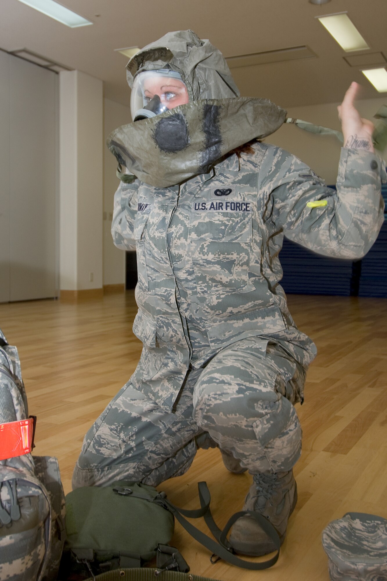 YOKOTA AIR BASE, Japan -- Airman Janet Conway, 374th Security Forces Squadron, quickly dons her chemical protective overgarment during an Ability to Survive and Operate Rodeo PAR team competition Sept. 17 at the Taiyo Community Center. Post attack reconnaissance teams from throughout the base went head-to-head to see who was best. The 374th Logistics Readiness Squadron won the competition. The ATSO Rodeo covered areas of emphasis such as contamination control, unexploded ordnance identification and marking and asset protection in a chemical environment. (U.S. Air Force photo/Osakabe Yasuo)

