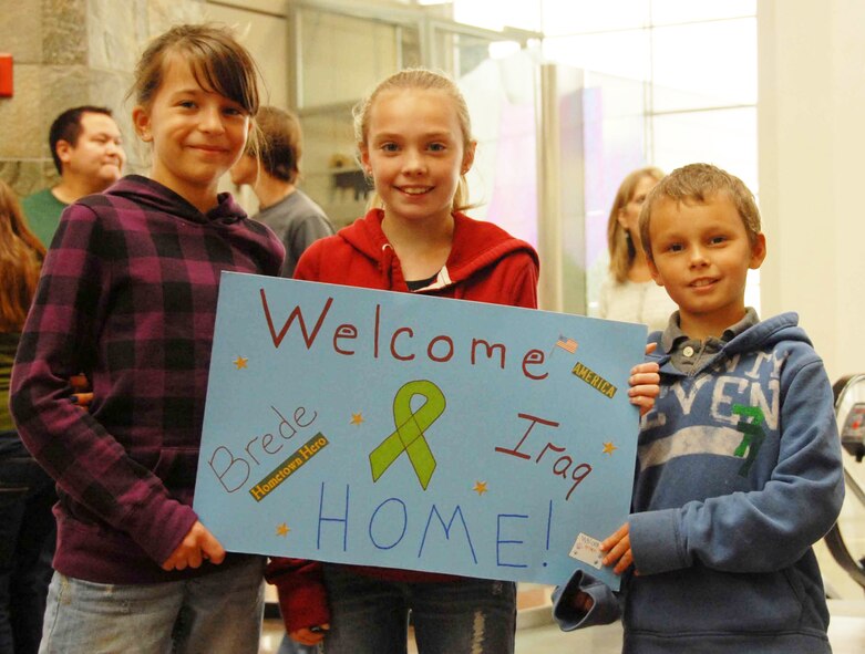 Brooke Lammers, Amber Weiss, and Caleb Bergeron hold a Welcome Home signs as they await for the return of Senior Master Sgt. Brede Emtman from his deployment at the Anchorage International Airport Sunday, Sept. 13.  Senior Master Sgt. Emtman is part of the 477th Fighter Group Civil Engineer Squadron and one of the 37 Airmen deployed to Kirkuk Air Base, Iraq, for the past four to six months. During their deployment, the Airmen worked with other Airmen, soldiers, and Iraqi fliers to repair roads and runway and reconstruct shrines for public use.  The Airmen also helped train and teach local nationals on several construction techniques.  The deployment was the first full unit deployment for the squadron and first for the 477th FG.  (Air Force Photo / Tech. Sgt. Craig Dunbar)