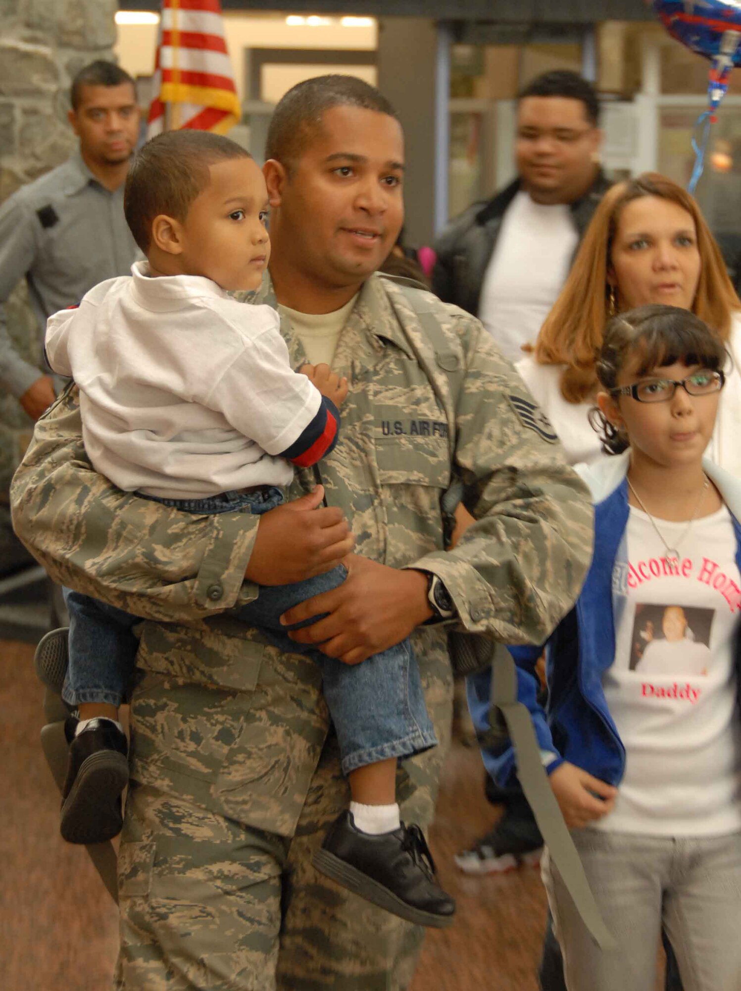 Staff Sgt. Teo Mejiaperalto holds his son for the first time in six months after returning home from a deployment to Iraq, as his wife and daughter walk with him through the Anchorage International Airport Sunday, Sept. 13.  Staff Sgt. Mejiaperalto is part of the 477th Fighter Group Civil Engineer Squadron and one of the 37 Airmen deployed to Kirkuk Air Base, Iraq, for the past four to six months. During their deployment, the Airmen worked with other Airmen, soldiers, and Iraqi fliers to repair roads and runway and reconstruct shrines for public use.  The Airmen also helped train and teach local nationals on several construction techniques.  The deployment was the first full unit deployment for the squadron and first for the 477th FG. (Air Force Photo / Tech. Sgt. Craig Dunbar)