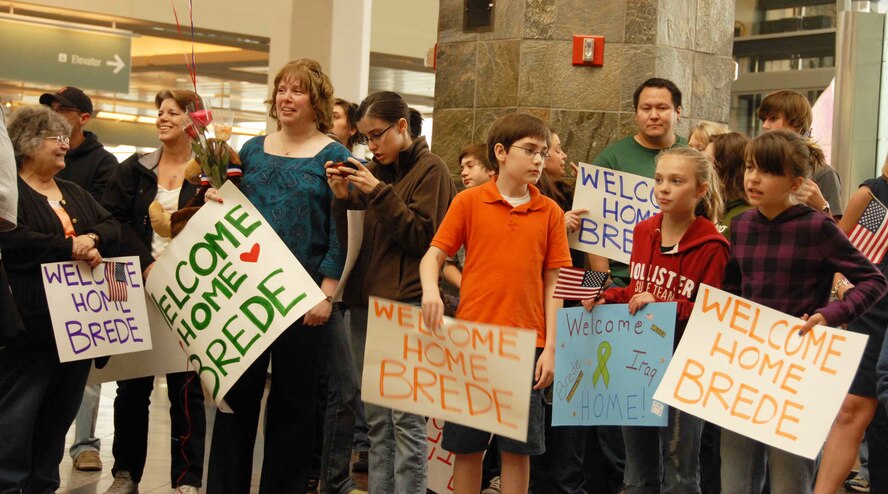 Family and friends of Senior Master Sgt. Brede Emtman hold posters anxiously awaiting his return from deployment at the Anchorage International Airport Sunday, Sept. 13. Senior Master Sgt. Emtman is part of the 477th Fighter Group Civil Engineer Squadron and one of the 37 Airmen deployed to Kirkuk Air Base, Iraq, for the past four to six months. During their deployment, the Airmen worked with other Airmen, soldiers, and Iraqi fliers to repair roads and runway and reconstruct shrines for public use. The Airmen also helped train and teach local nationals on several construction techniques. The deployment was the first full unit deployment for the squadron and first for the 477th FG. (Air Force Photo / Tech. Sgt. Craig Dunbar)