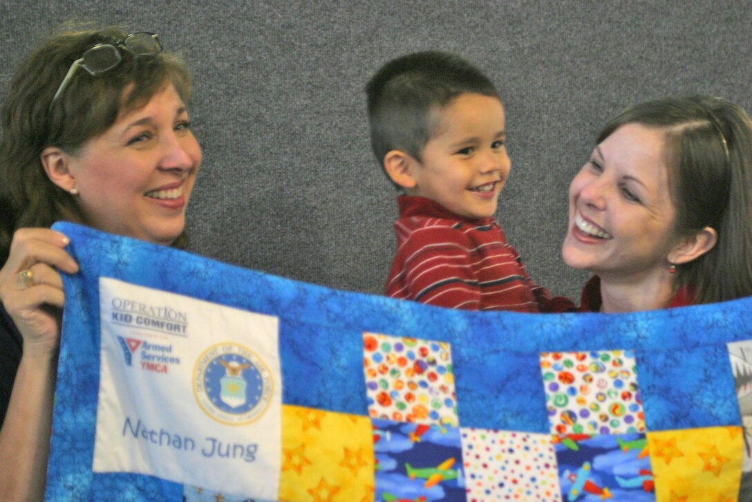 Giselle Schneider, an Operation Kid Comfort volunteer, meets Cathy Jung and son Nathan. Mrs. Schneider works on Operation Kid Comfort quilts every day because she said service members work on behalf of America every day. (U.S. Air Force photo/Master Sgt. Paul Dean)