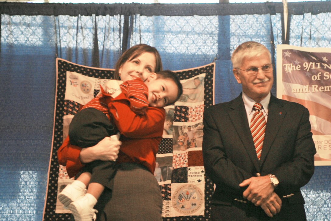Nathan Jung, son of Tech. Sgt. John and Cathy Jung, received an Operation Kid Comfort quilt at a ceremony Sept. 11, 2009. Sergeant Jung deployed to Afghanistan in July. Operation Kid Comfort is an Armed Services YMCA program whose volunteers have made and distributed 6,000 quilts since 2004. Mike Landers (right) is the deputy national director of the AF YMCA. (U.S. Air Force photo/Master Sgt. Paul Dean)