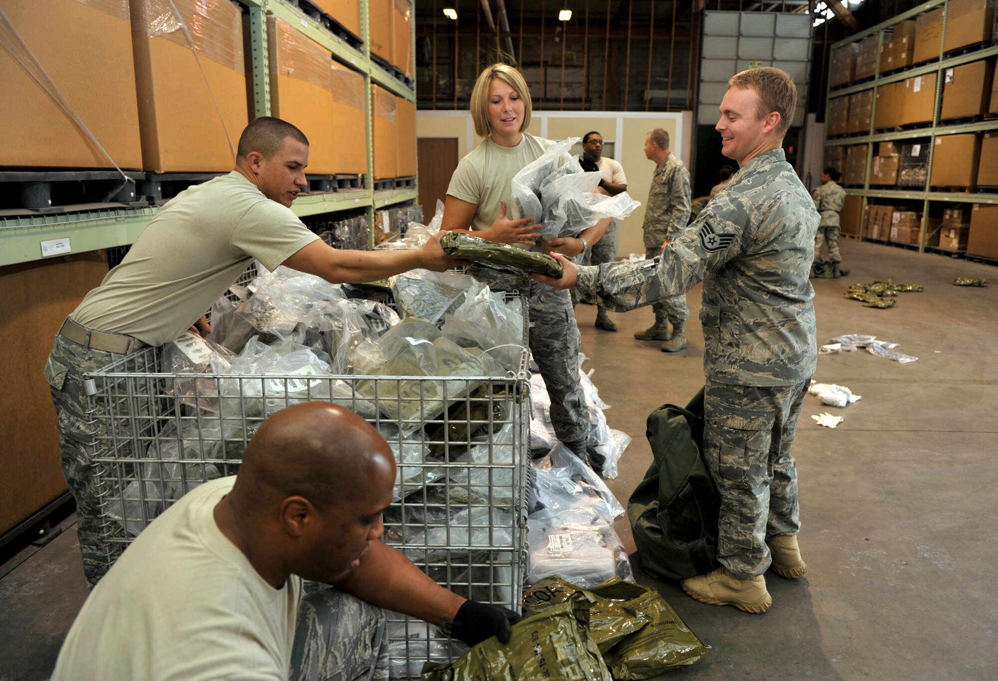 Airman 1st Class Kyle Williams gives a vacuum-sealed piece of protective equipment to Staff Sgt. Brian Reed (on right) inside a supply building at McConnell Air Force Base, Kan. Sergeant Reed and other Reservists assigned to the 931st Air Refueling Group gathered equipment during their September drill weekend to prepare for upcoming training events with active-duty Airmen at McConnell. Airman Williams was one of several active-duty Airmen from the 22nd Logistics Readiness Squadron who worked on a Saturday to issue equipment to 931st Reservists. (U.S. Air Force photo/Tech. Sgt. Jason Schaap)