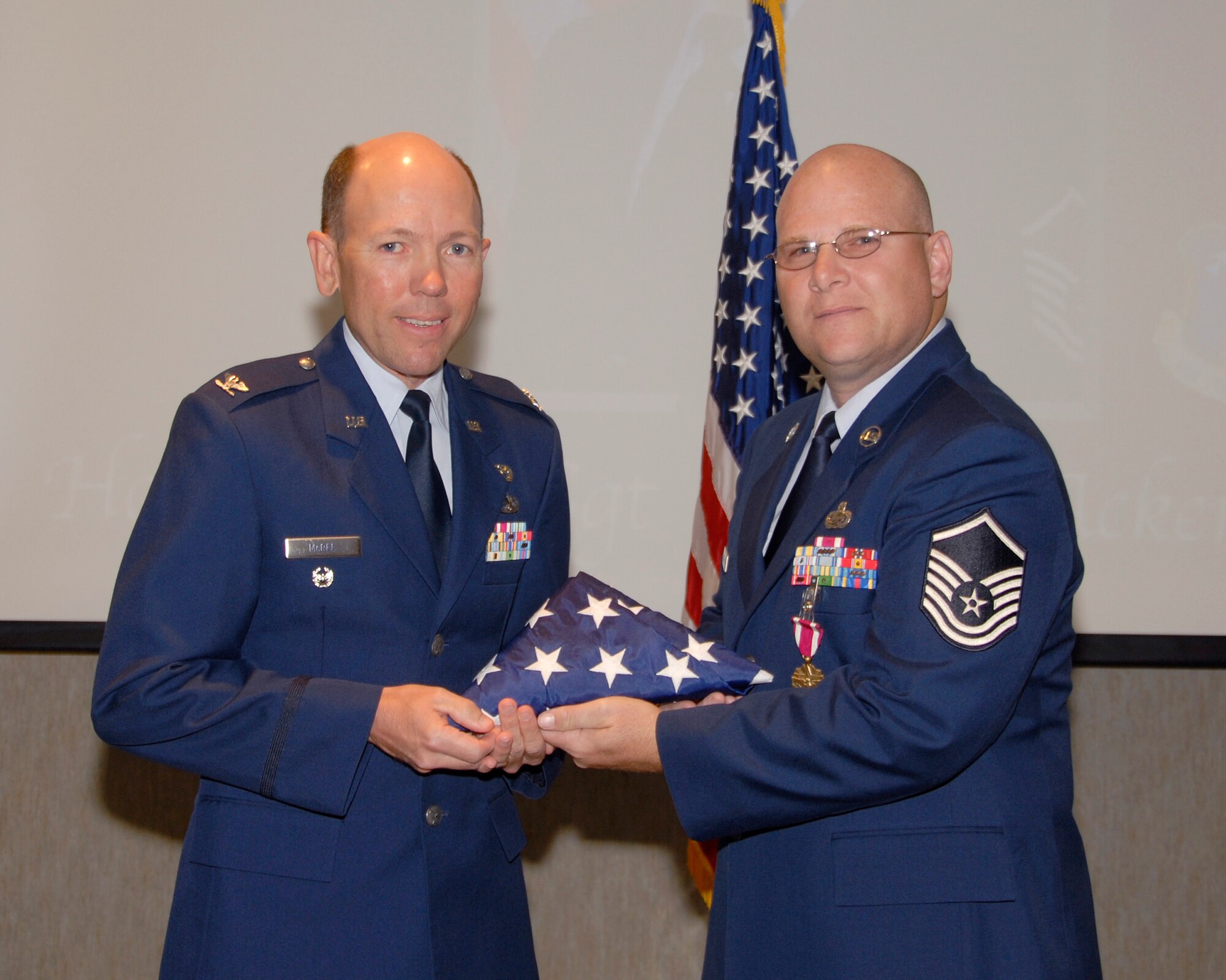 McGHEE TYSON ANGB, Tenn. -- Master Sgt. Dwayne D. Ackerman, a physical fitness instructor with The I.G. Brown Air National Guard Training and Education Center,  is presented the United States flag by Col. Bradley McRee during his retirement ceremony from the U.S. Air Force, which was held on the campus of the Training and Education Center here, Sep. 11, 2009.  Ackerman was stationed at the TEC for a total of 17 years and held instructor positions with the Noncommissioned Officer Leadership School, the Noncommissioned Officer Academy and the Academy of Military Science. (U.S. Air Force photo by Master Sgt. Kurt Skoglund)(Released)