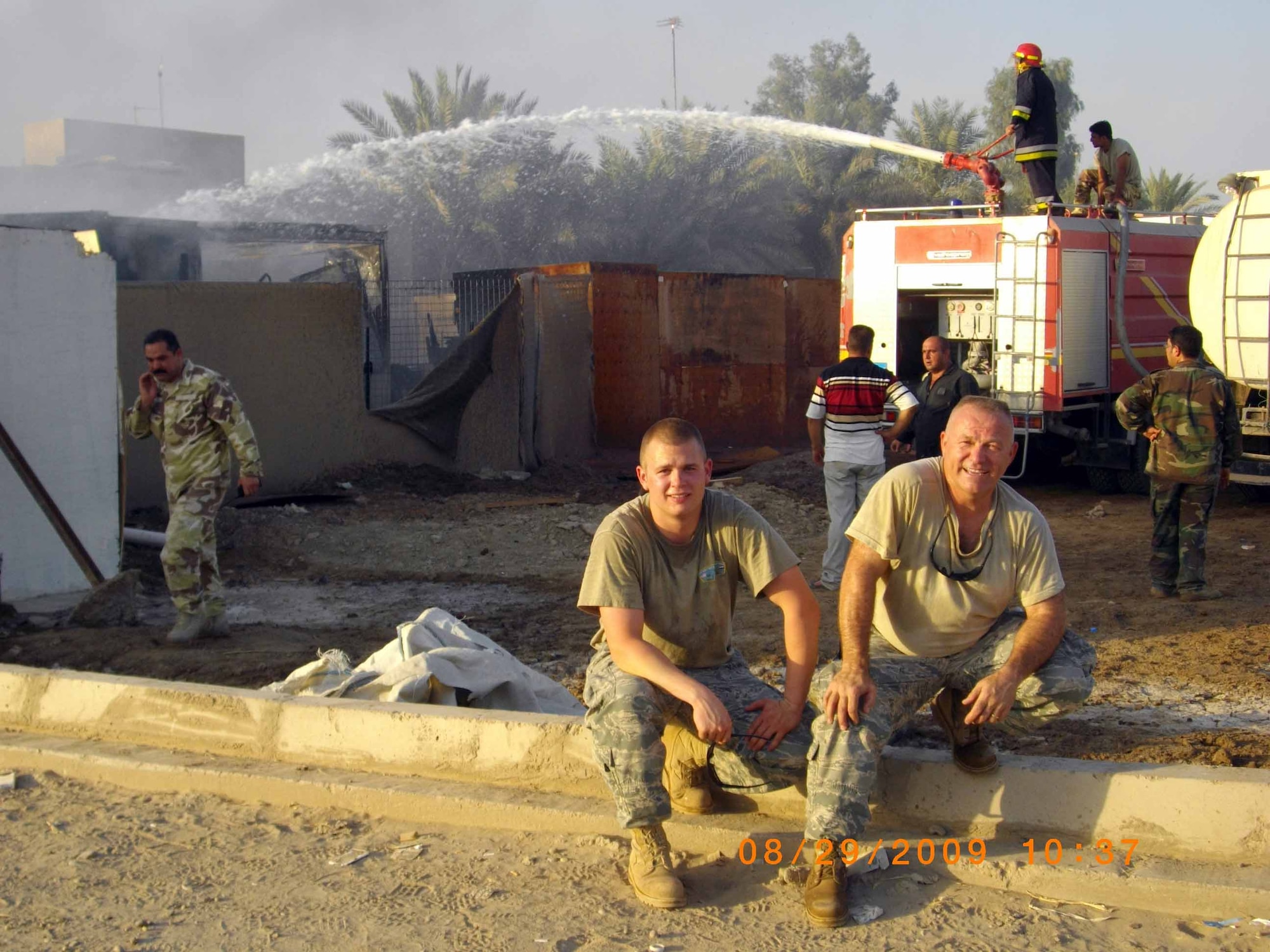 Senior Master Sgt. Judson Shull and Airman 1st Class Robert Bissett take a load off after fighting a fire in an Iraqi housing development  The two were off-base when a fire broke out in the nearby neighborhood.